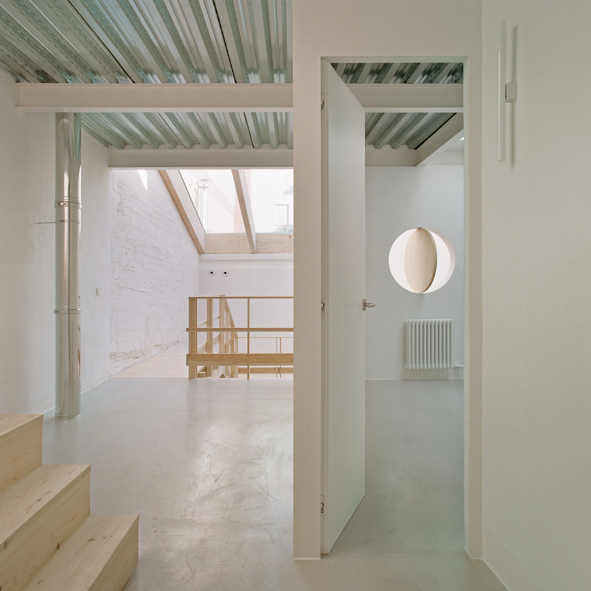 Villa V by Andrea Arriola Fiol and Adrián Mellado Muñoz, photographed by Del Rio Bani — A threshold on the upper floor, the timber stair on one side and a round opening framed through an open door