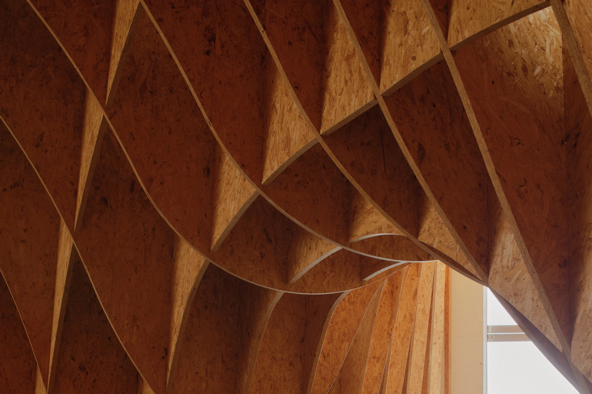 Autobahnkirche Siegerland by schneider+schumacher, photographed by David Altrath — Interior close view of the interlocking timber ribs of the gridshell with a sliver of window light at the edge.