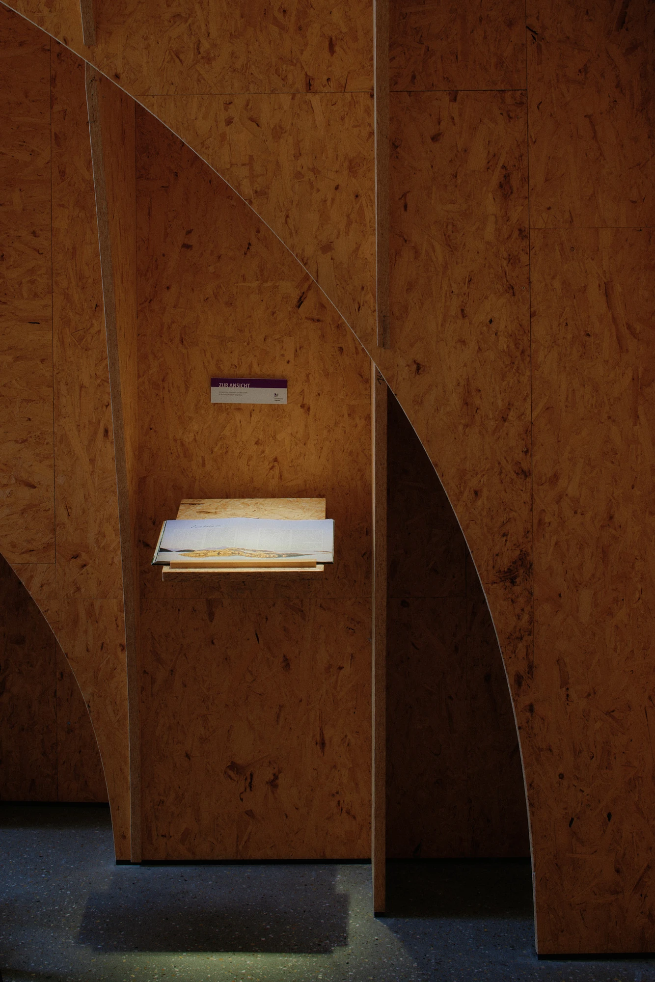 Autobahnkirche Siegerland by schneider+schumacher, photographed by David Altrath — Interior view of a small publication stand set into a niche in the timber wall.