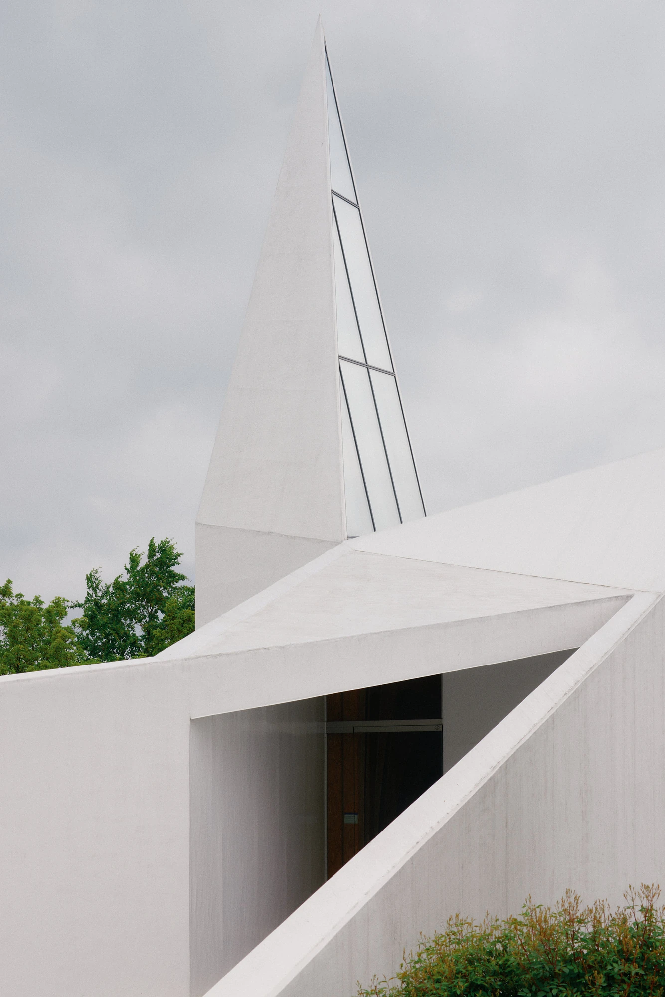 Autobahnkirche Siegerland by schneider+schumacher, photographed by David Altrath — Exterior close view of one pointed spire and its glazed edge rising above the white entrance.