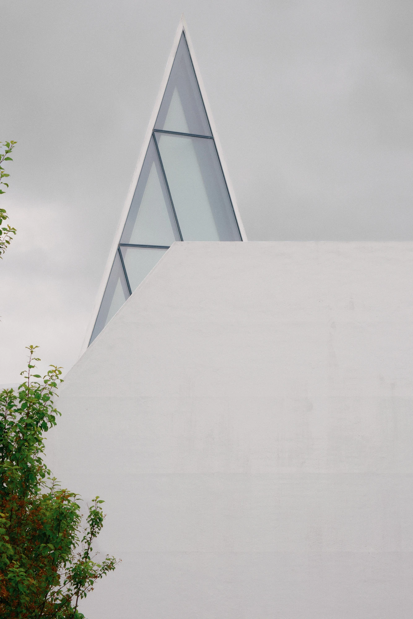Autobahnkirche Siegerland by schneider+schumacher, photographed by David Altrath — Exterior view of one glazed spire tip rising above the angular white volume against an overcast sky.