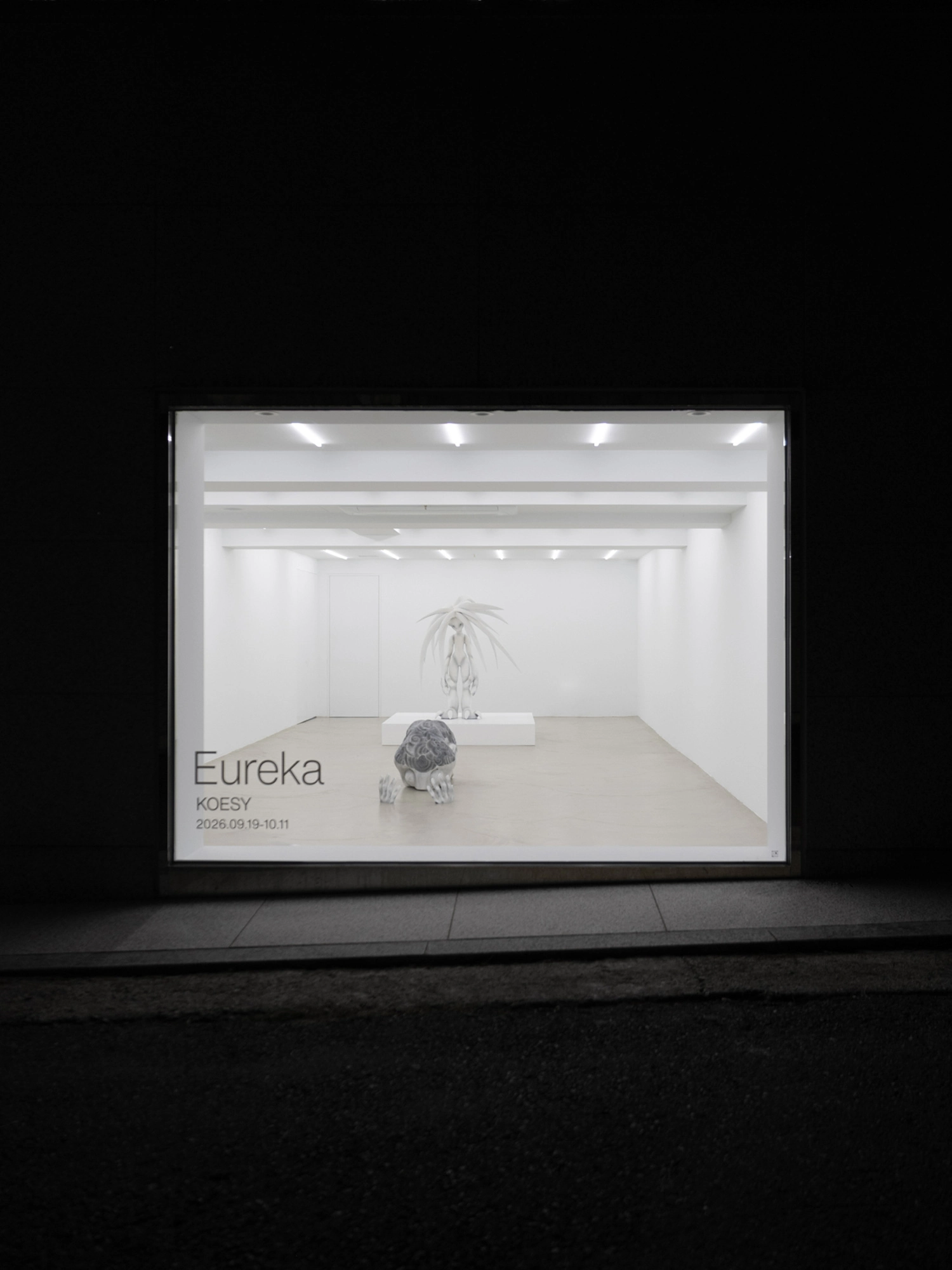 Eureka by Koesy — The gallery front at night, the show's name lettered on the glass.