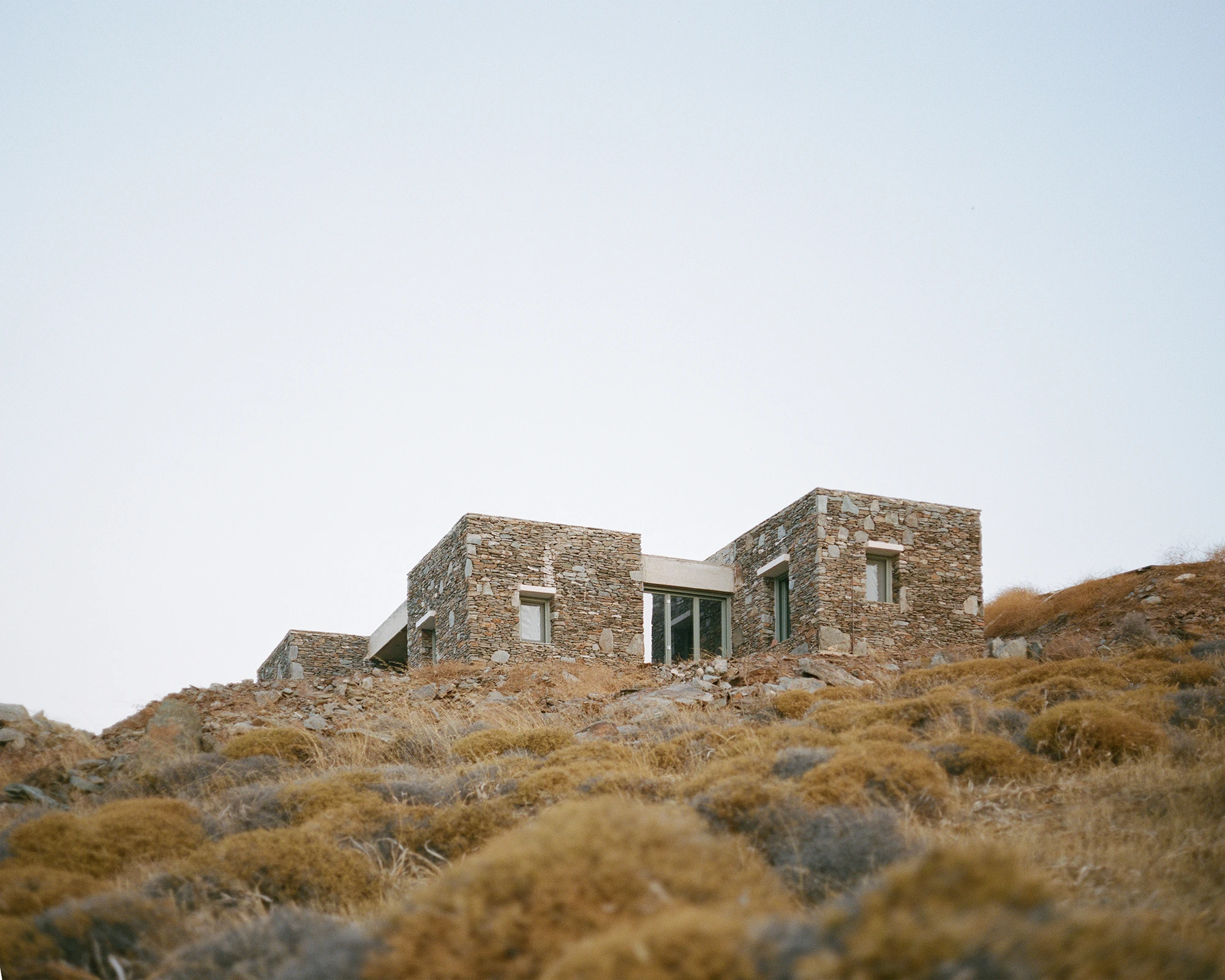 House Thermia by RAUM, photographed by Benoit Chailleux — A close view up the slope toward the house at Thermia.