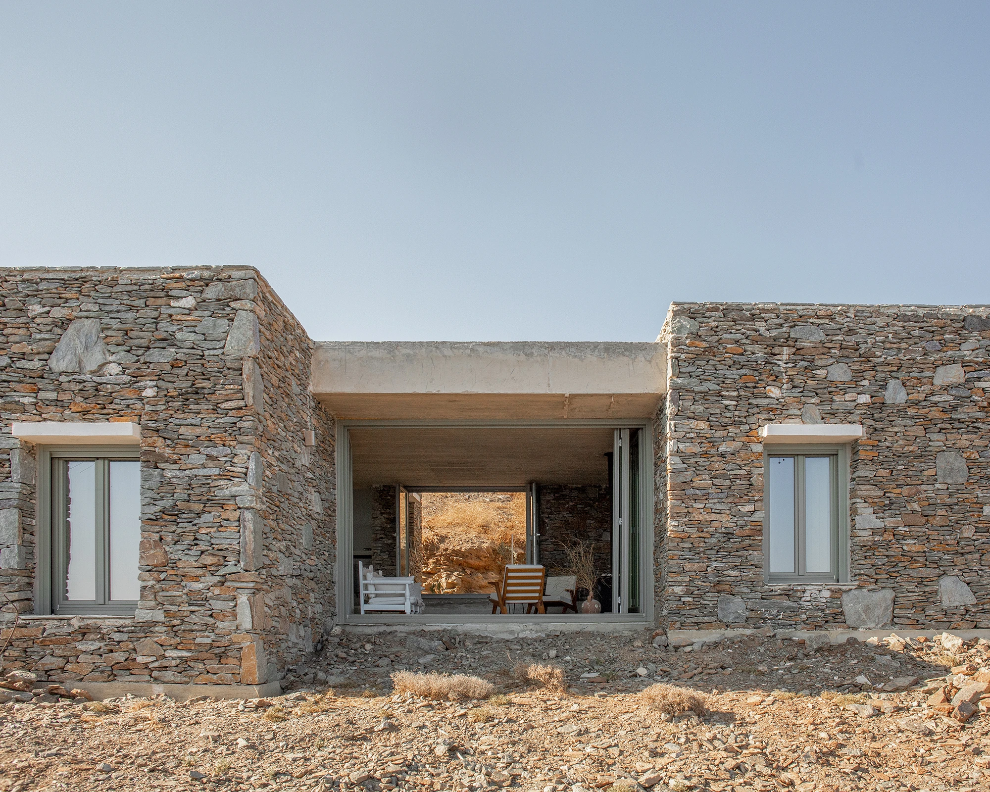 House Thermia by RAUM, photographed by Benoit Chailleux — An interior looking out through a doorway to the terrace and sea at Thermia.