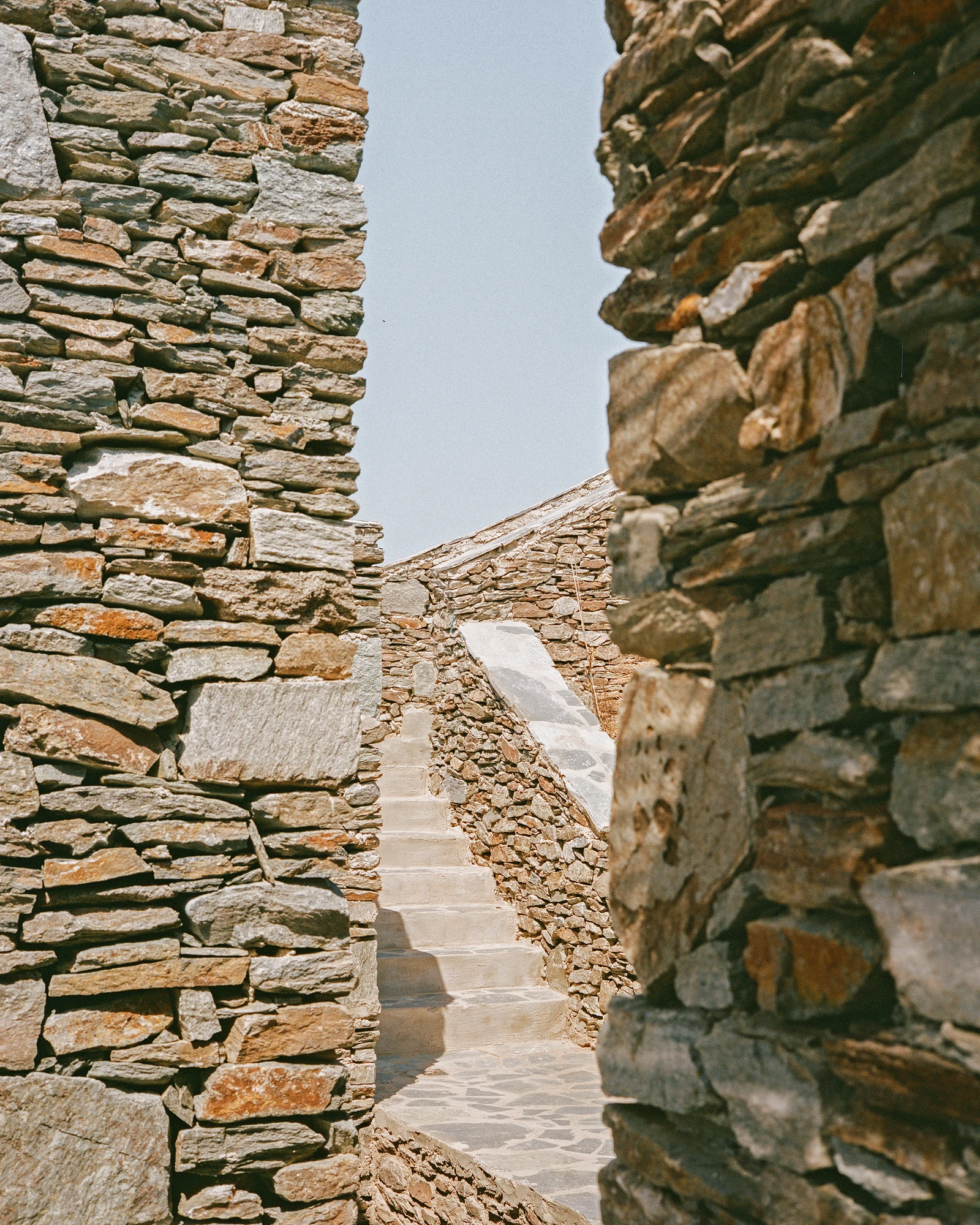 House Thermia by RAUM, photographed by Benoit Chailleux — A passage and steps between the walls of the house at Thermia.