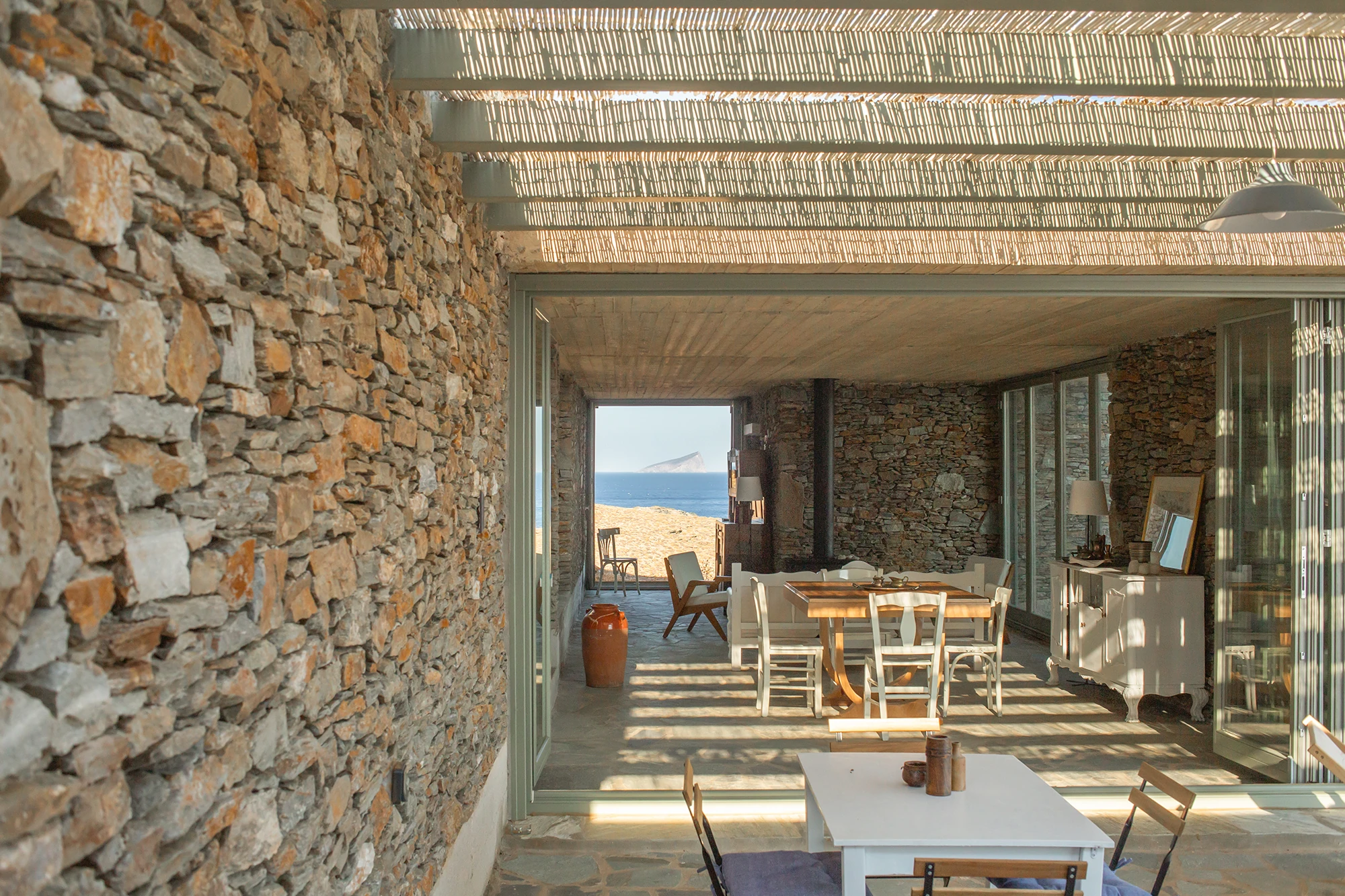 House Thermia by RAUM, photographed by Benoit Chailleux — The living room opening onto the terrace with the sea beyond at Thermia.