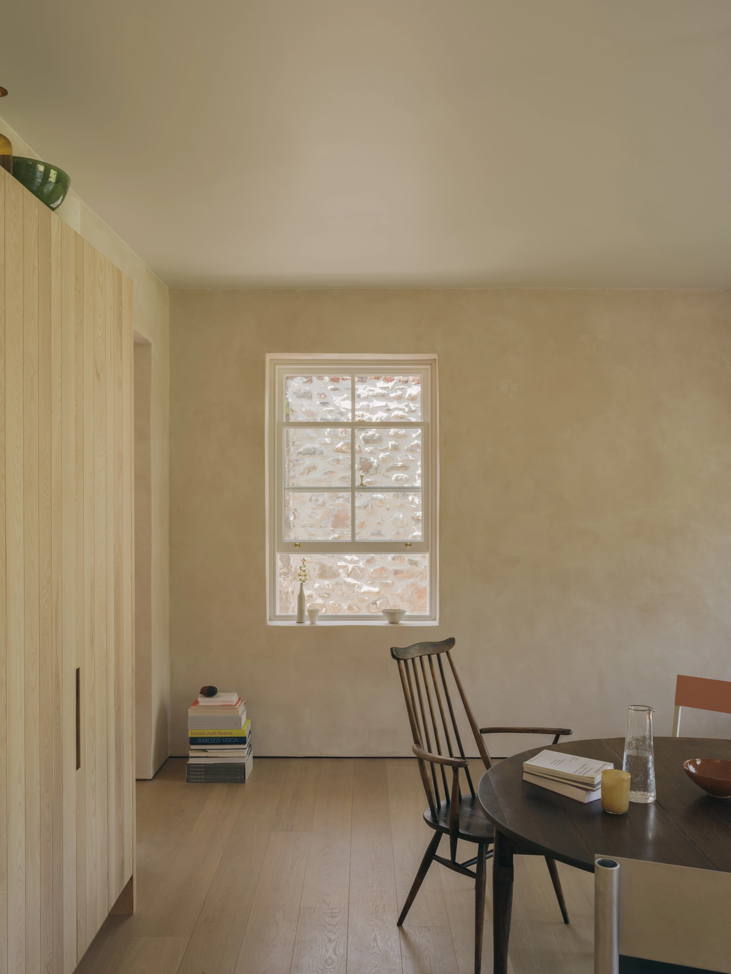 Cairngorm Cottage by Architecture Office, photographed by Richard Gaston — A window framing the granite outside, beside tall ash cupboards in the dining room.