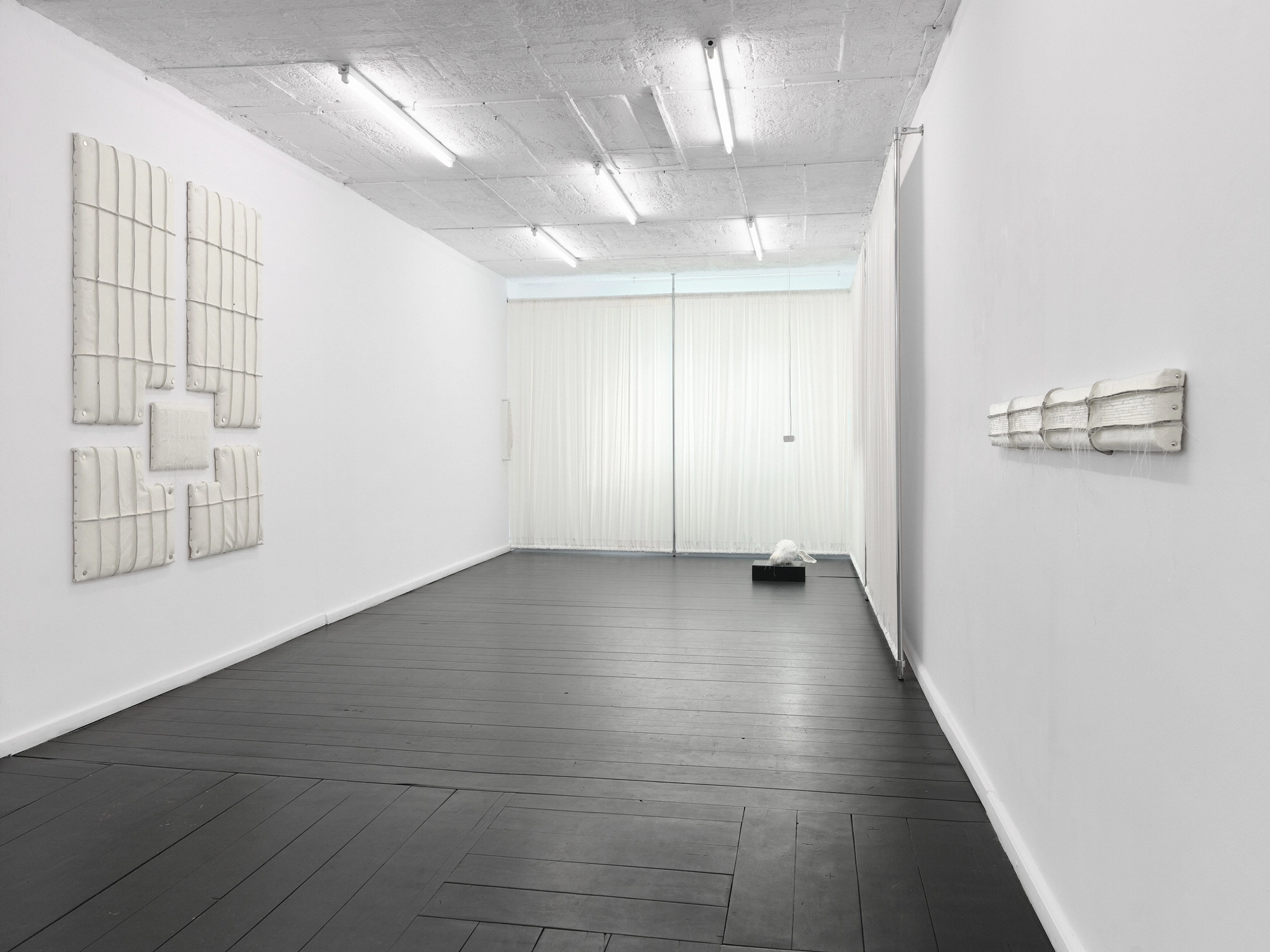 Within and For Each Other by Jan Baszak, photographed by Bartosz Górka — Exhibition view toward the curtained end of the room, Relief 03 on the left wall and Relief 02 on the right.