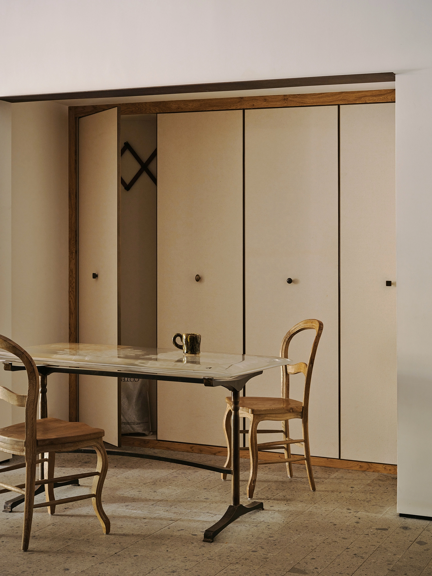 Conceived by Cotemp by ONOAA STUDIO, photographed by Jonathan Leijonhufvud — A table and two chairs before a wall of doors.