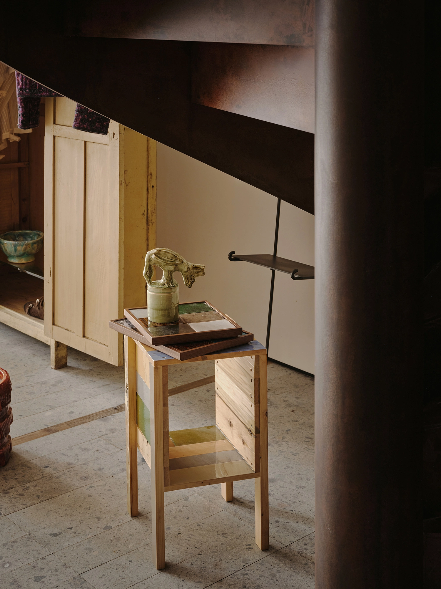 Conceived by Cotemp by ONOAA STUDIO, photographed by Jonathan Leijonhufvud — A side table under the raw steel staircase, with a cabinet behind.