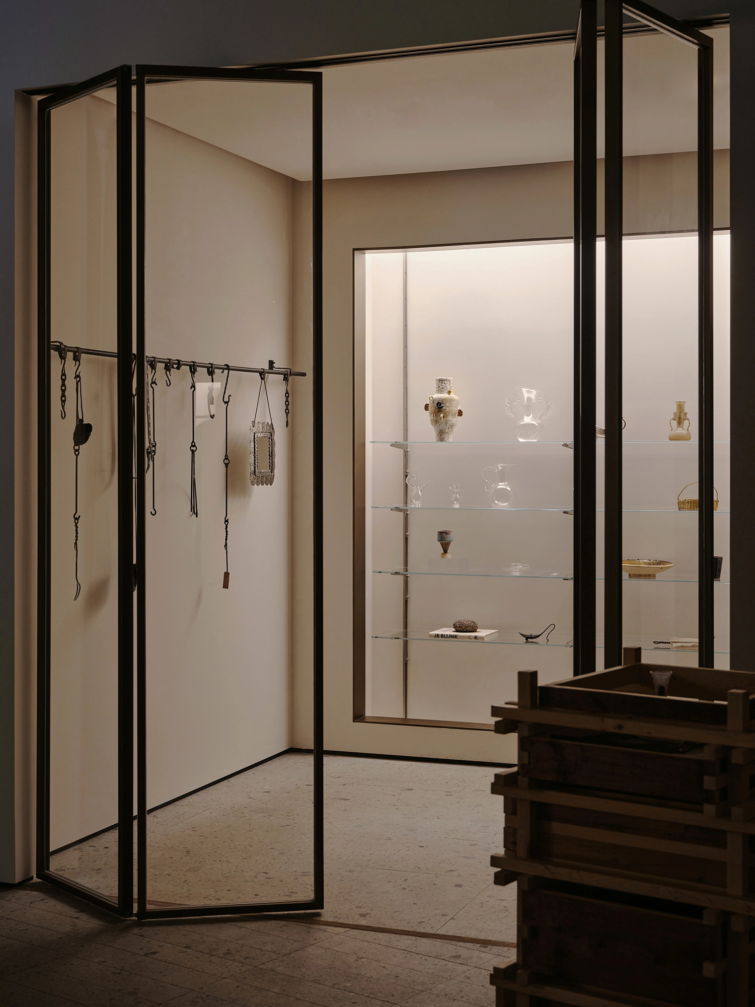 Conceived by Cotemp by ONOAA STUDIO, photographed by Jonathan Leijonhufvud — A glass-framed partition hung with small accessories beside a lit display niche.