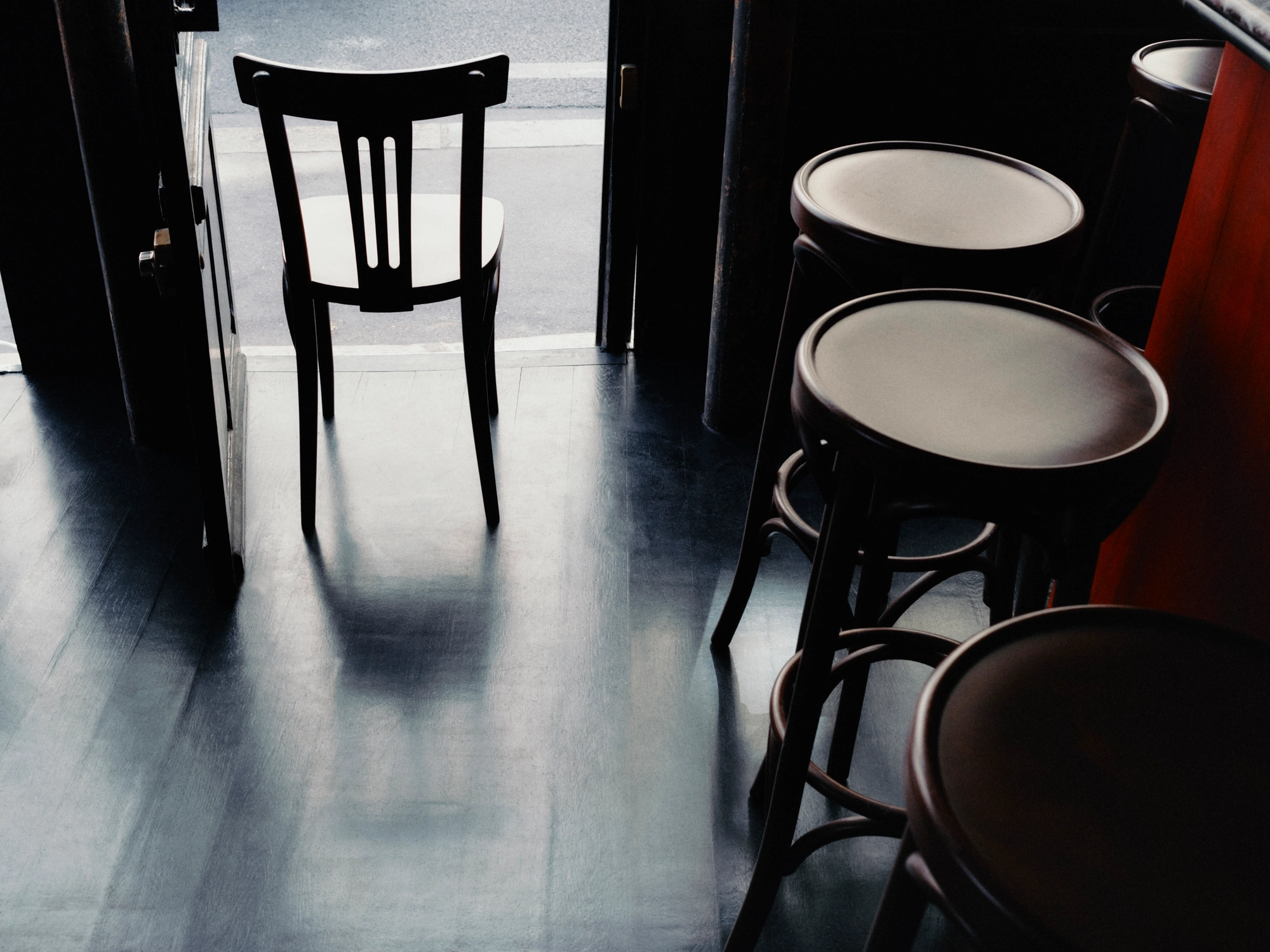 WINONA by Romain Basile Petrot, photographed by Romain Roucoules, Carla Beaujardin — A chair and a row of stools at the base of the counter, reflected in the glossy black floor.