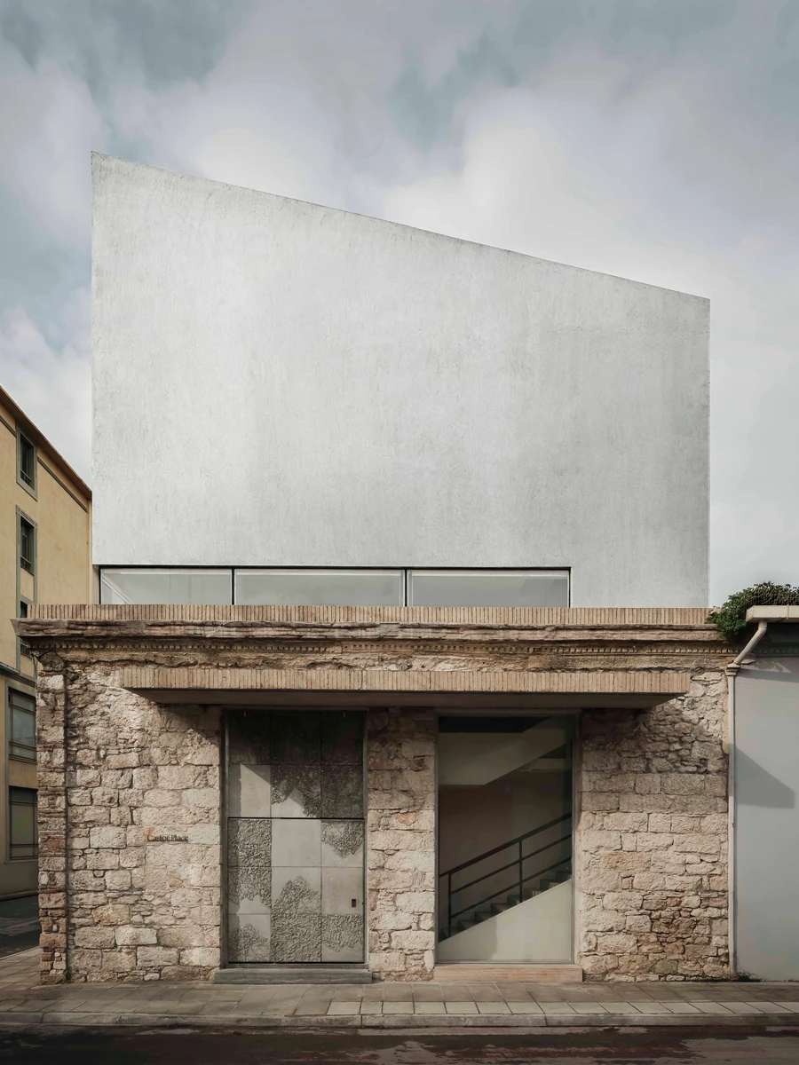 Castor Place by MPNYC, photographed by Yiorgos Kaplanidis — Front of Castor Place with the liquid metal volume above the stone ground floor and its reclaimed brick entrance canopy
