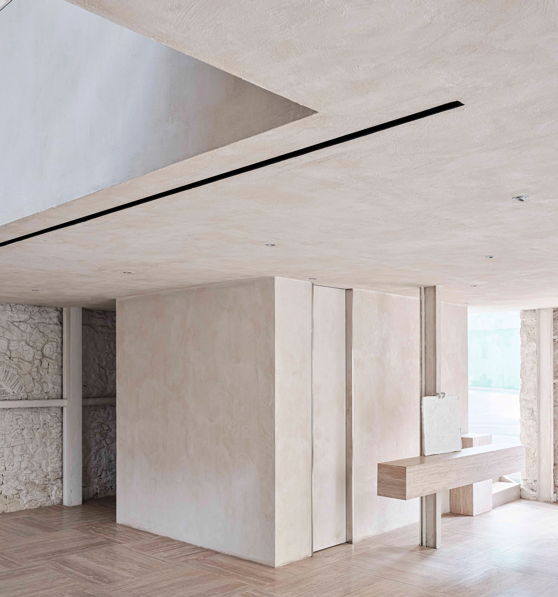 Castor Place by MPNYC, photographed by Yiorgos Kaplanidis — A lime stucco interior meeting the exposed stone, a slim bench beside a bright opening