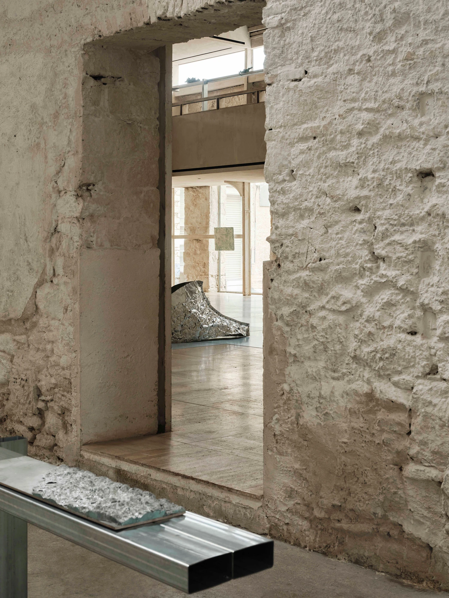 Castor Place by MPNYC, photographed by Yiorgos Kaplanidis — Installation view of Casting Water by Stefania Strouza, an aluminium work seen through a stone opening