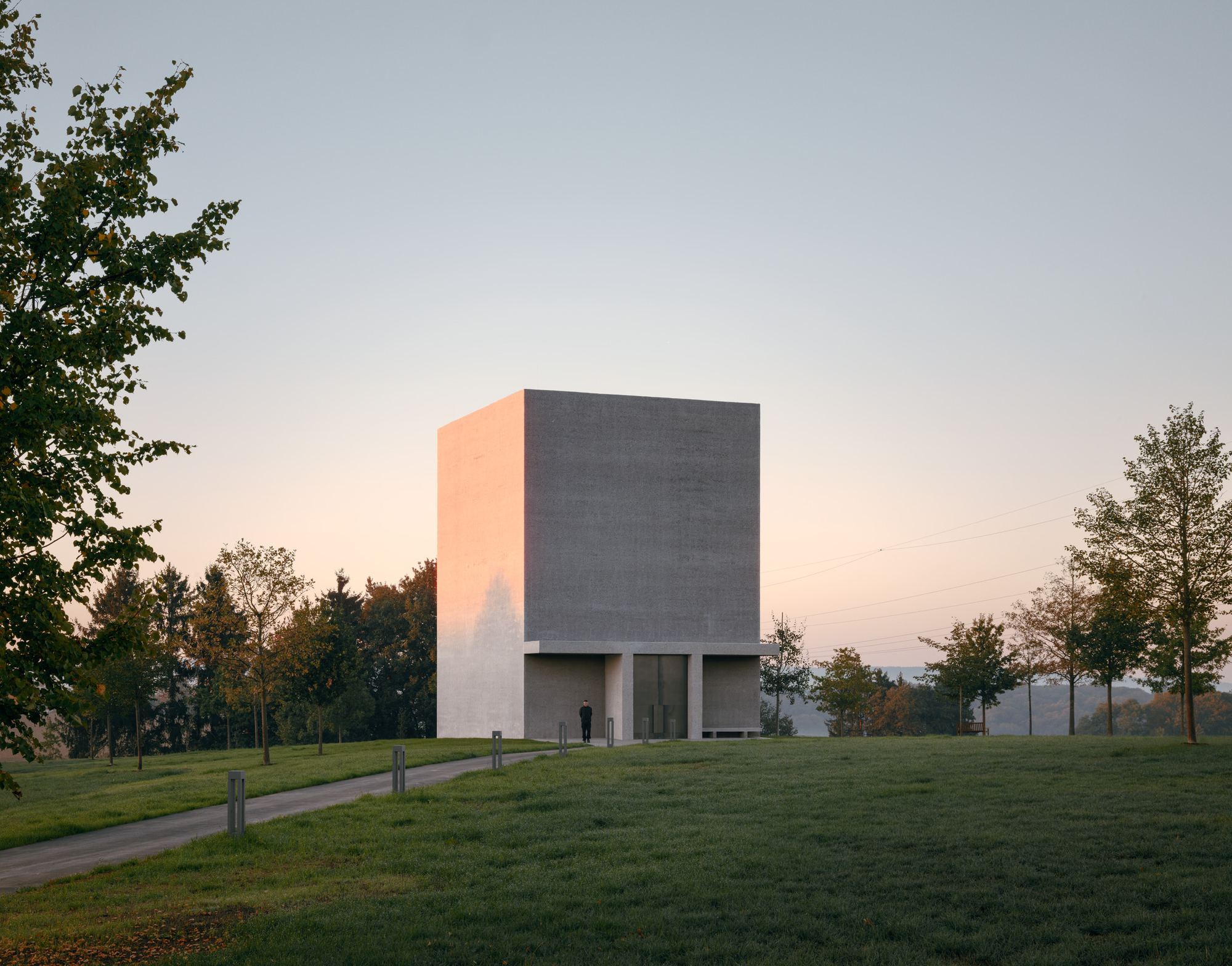 Anselm Kiefer Pavilion by David Chipperfield Architects, photographed by Simon Menges — The pavilion seen head-on across the sculpture garden, a bush-hammered concrete volume with the portico at its base