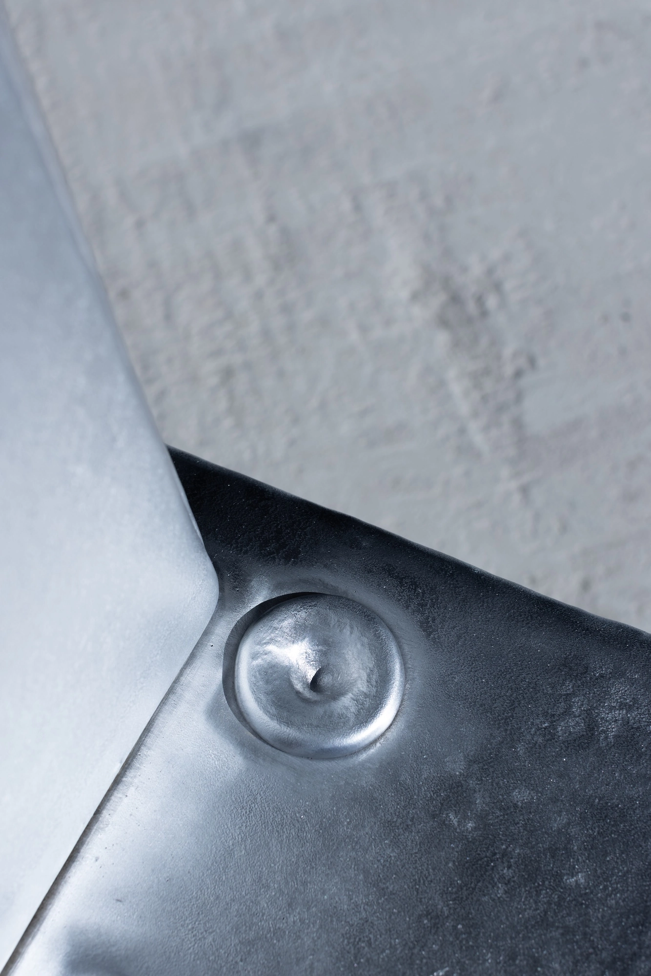 Ingot by Marc Sweeney, photographed by Marc Sweeney — Macro detail of a single round pour point, a shallow dimple with a central point in the cast seat plate.