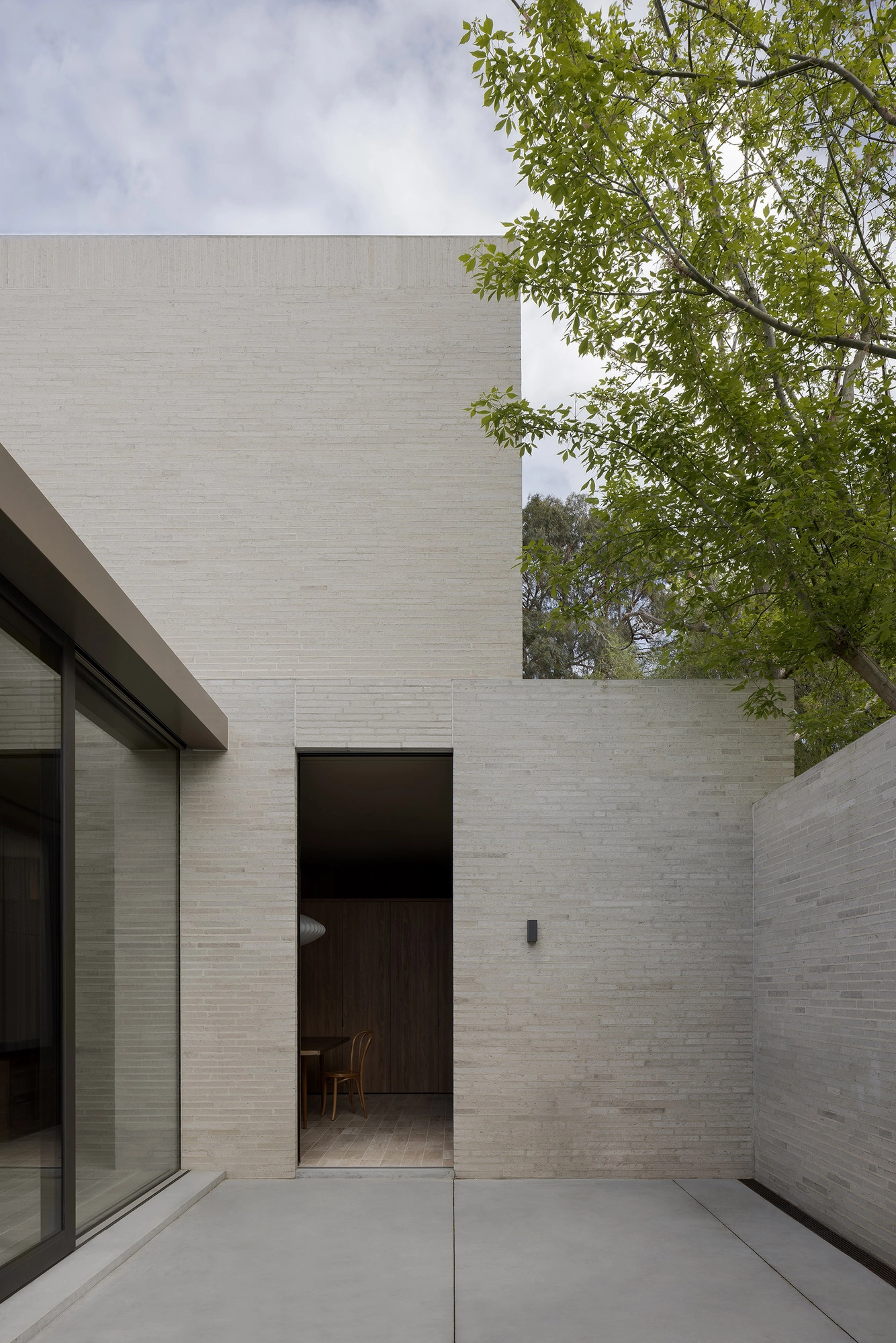 Casa Piva by B.E. Architecture, photographed by Timothy Kaye — The internal courtyard open to the sky, a glazed wall and a doorway set into the brick.