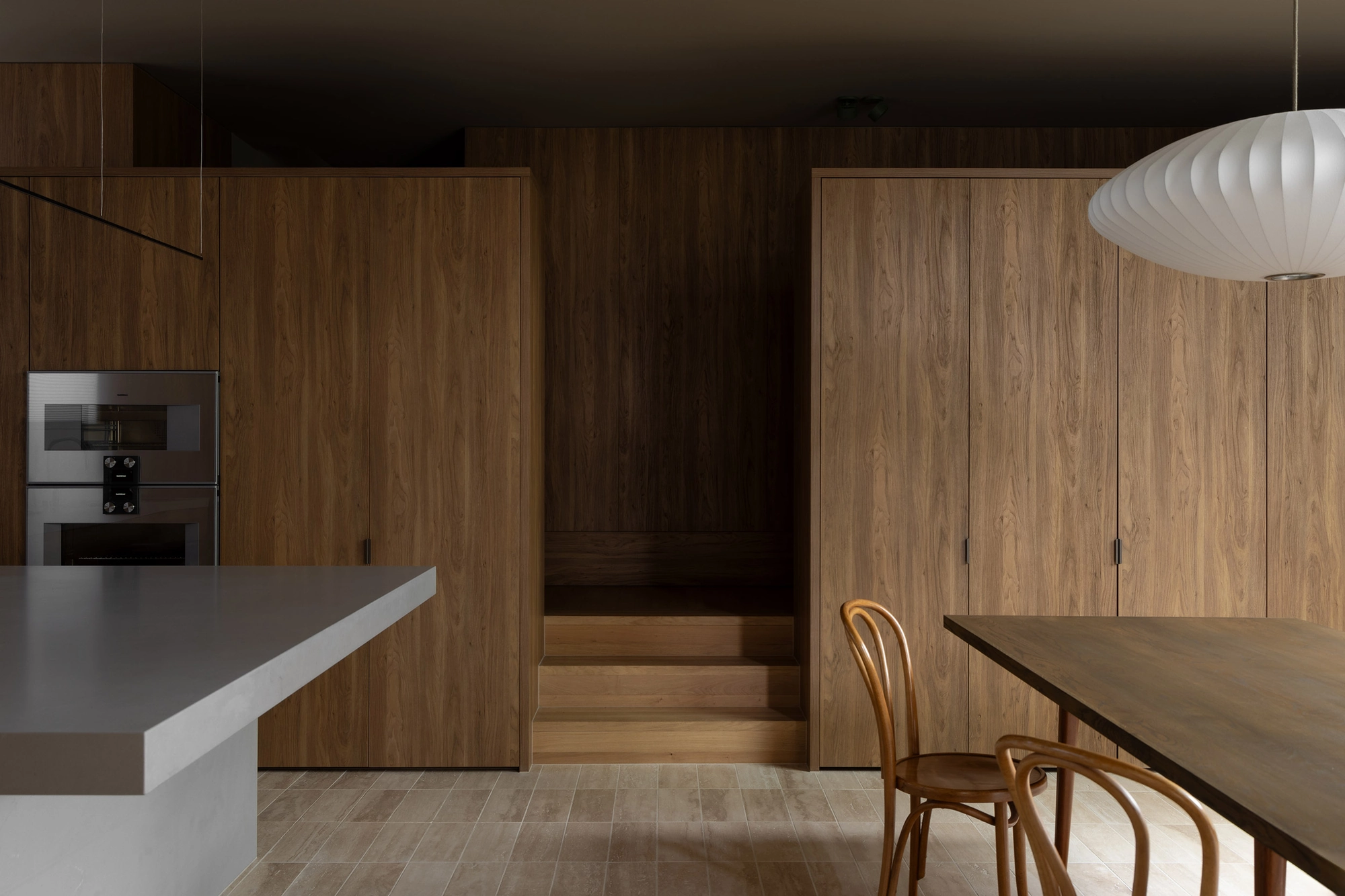 Casa Piva by B.E. Architecture, photographed by Timothy Kaye — The kitchen and dining area wrapped in antique oak joinery, with low steps rising between the two.