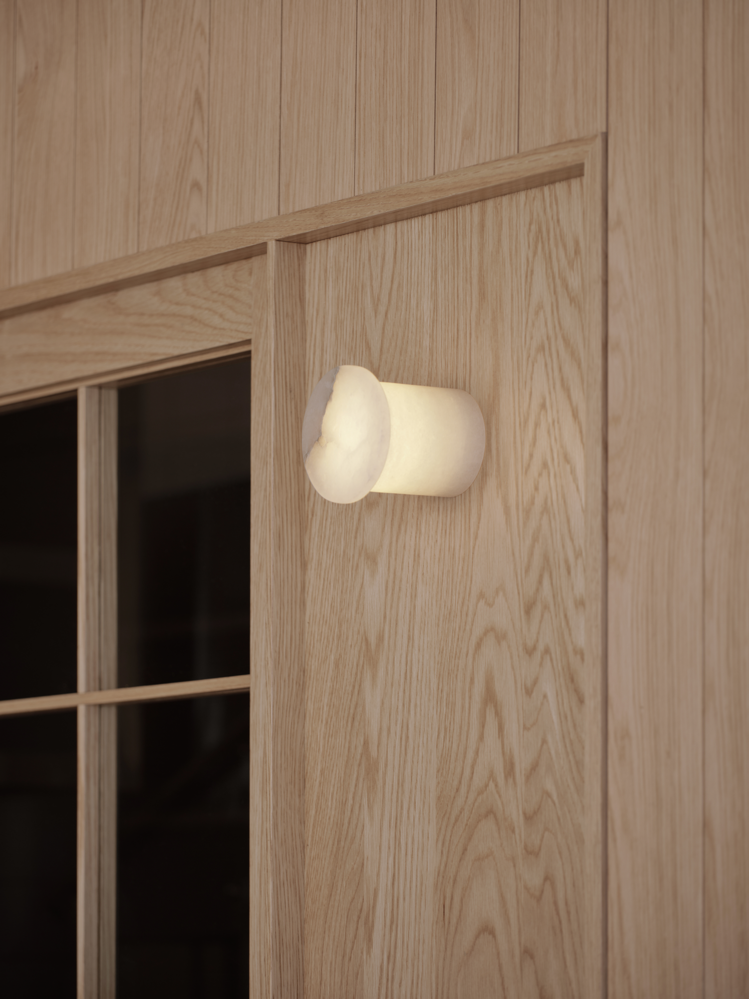 Bread&Walk by StudioFA, photographed by Dongkyu Kim — A rounded wall light glows beside a small paned window set into the wall.