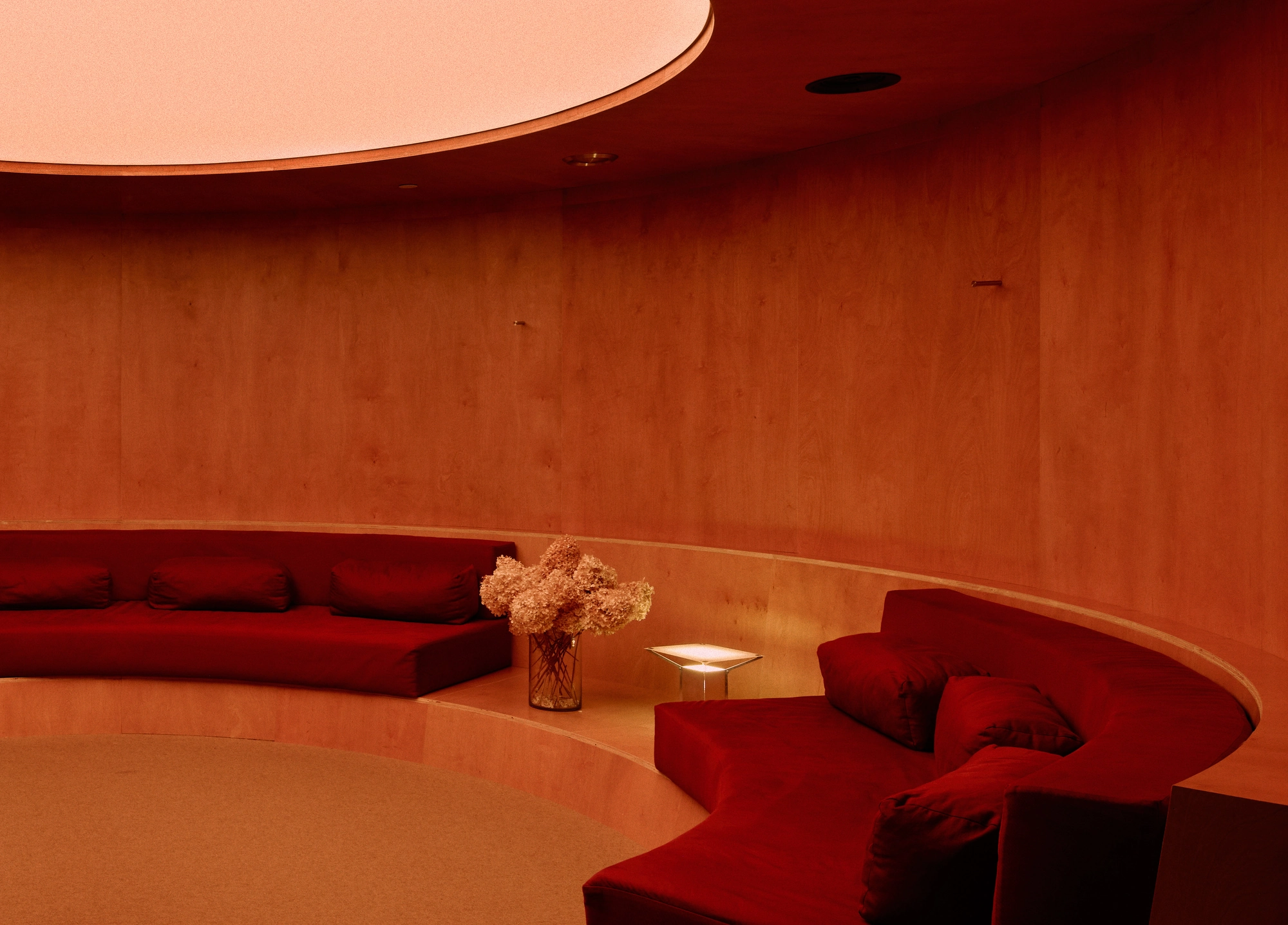 The Altar by MV-LLC — The circular IV Drip Lounge, a wood-clad room ringed with seating beneath a round overhead light.