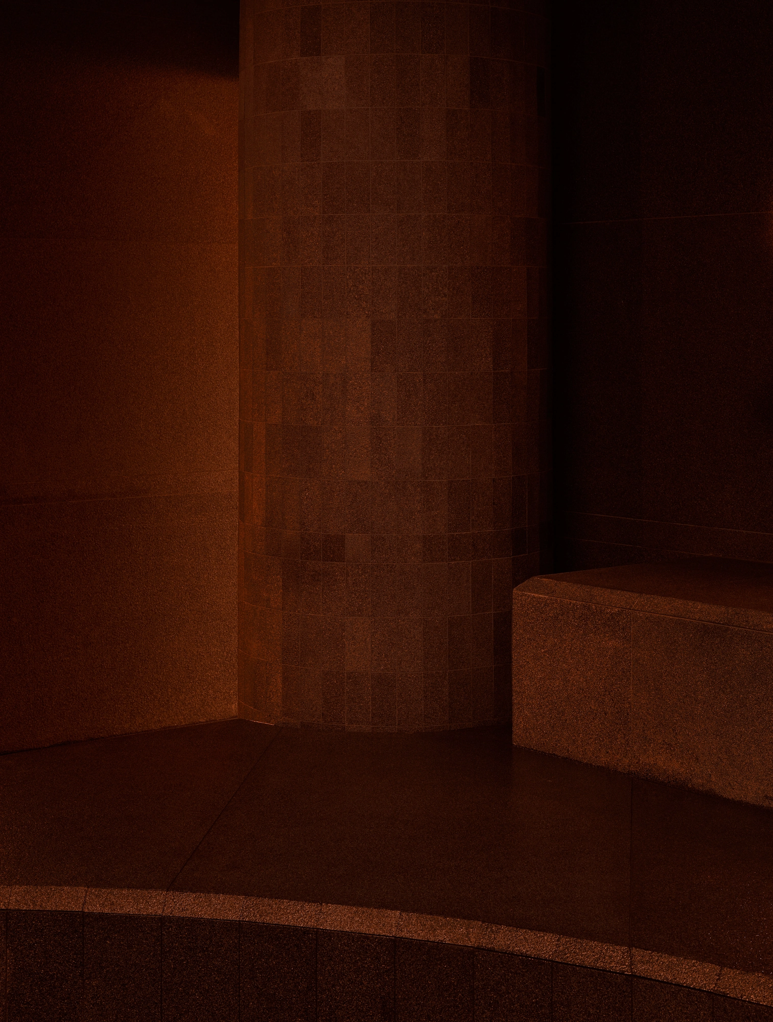 The Altar by MV-LLC — A column clad in small stone tile meets the stone perimeter bench in a corner of the atrium.