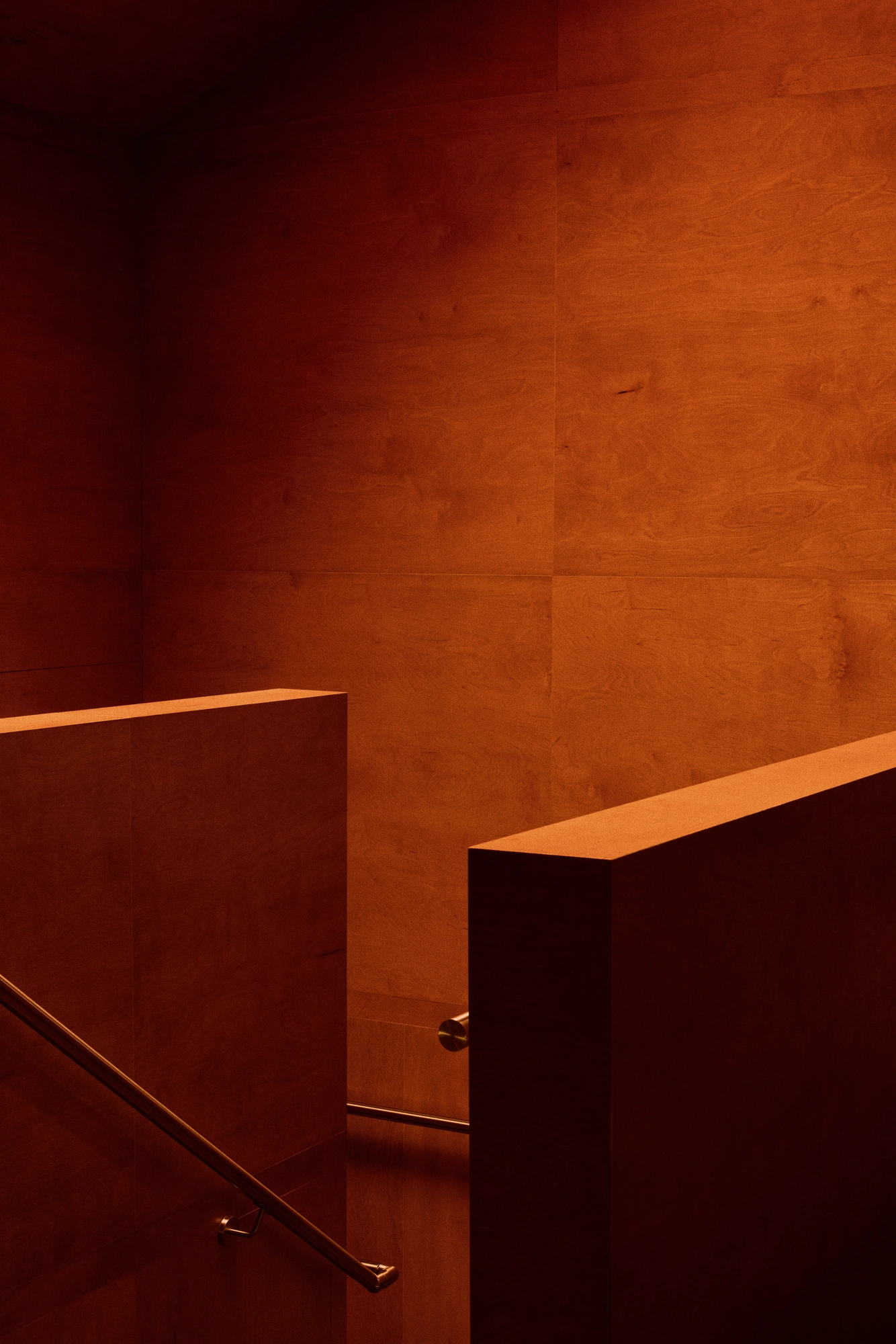 The Altar by MV-LLC — A solid handrail held back from the wood-paneled wall of the stairwell.
