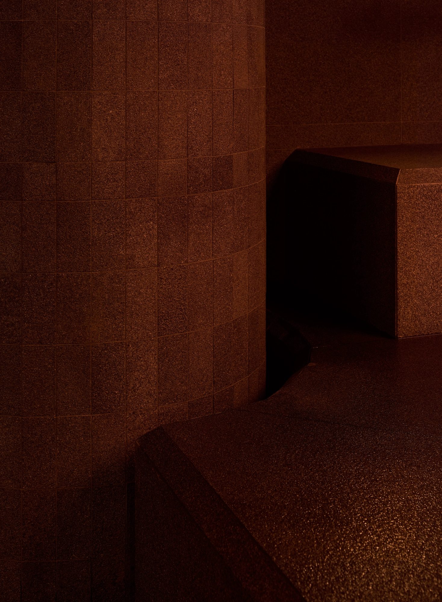 The Altar by MV-LLC — A detail of the small stone tile cladding an atrium column where it meets the stone seating.