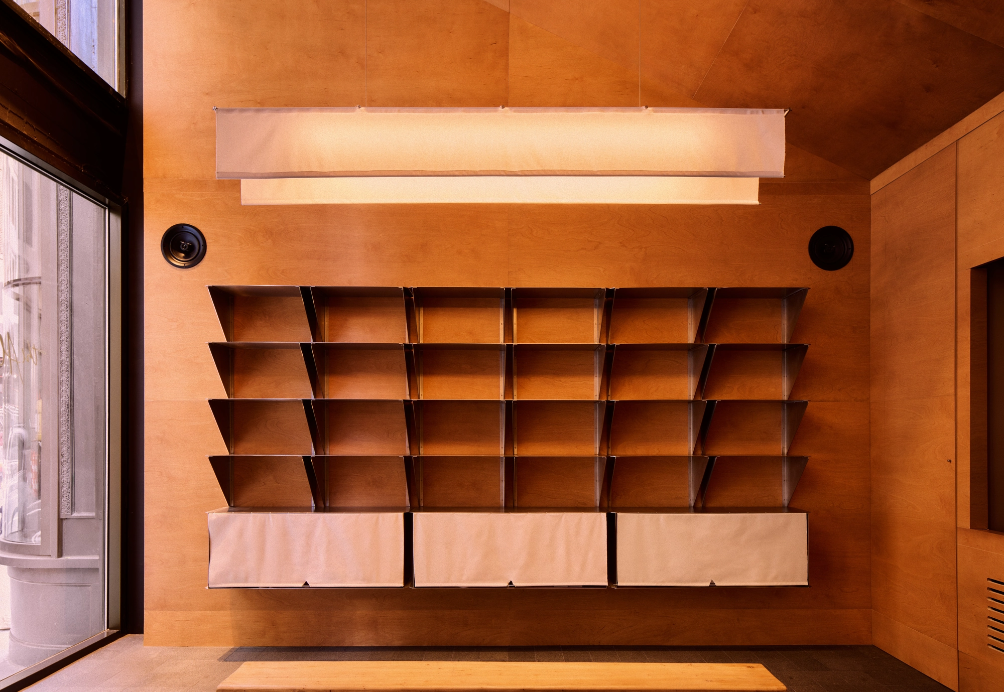 The Altar by MV-LLC — The entry reception, where triangular stainless steel display shelving is set into the wood paneling.