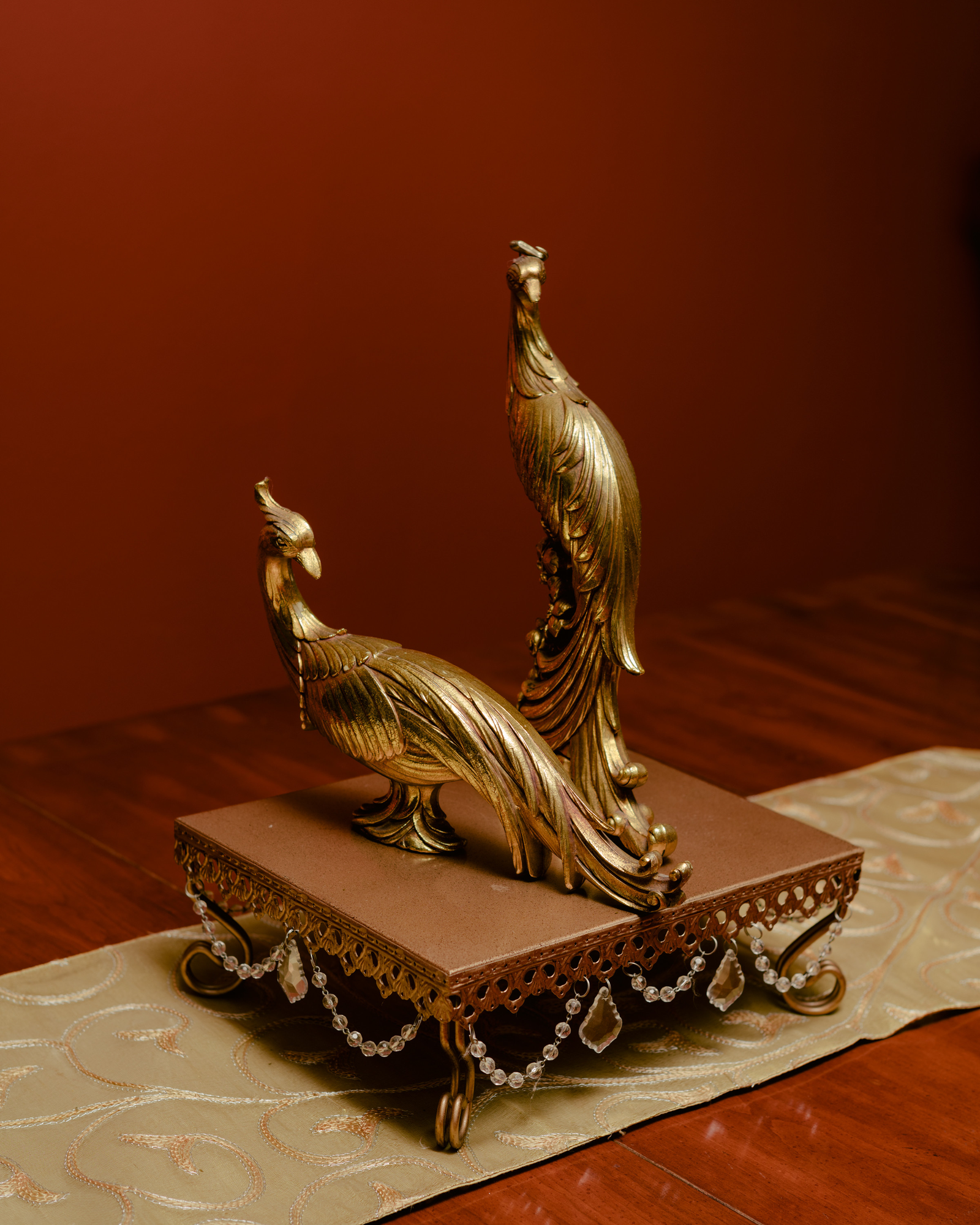 Paradise by Daniel Dorsa, photographed by Daniel Dorsa — Two gold bird ornaments on a footed tray, with a red wall behind.