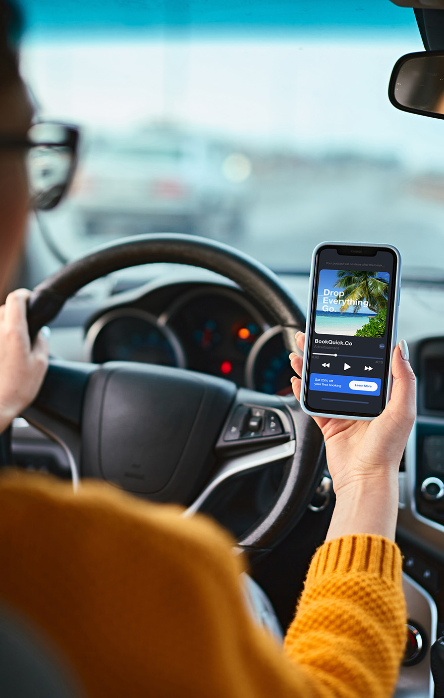 Woman looking at a travel ad on her phone while driving.