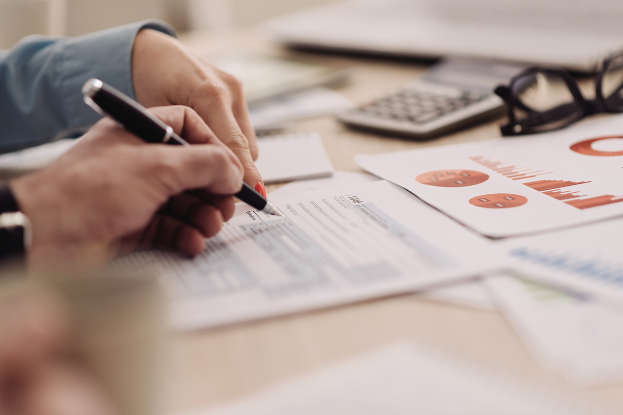 two-people-s-hands-working-on-small-business-taxes-at-desk-with-papers-glasses-and-calculator