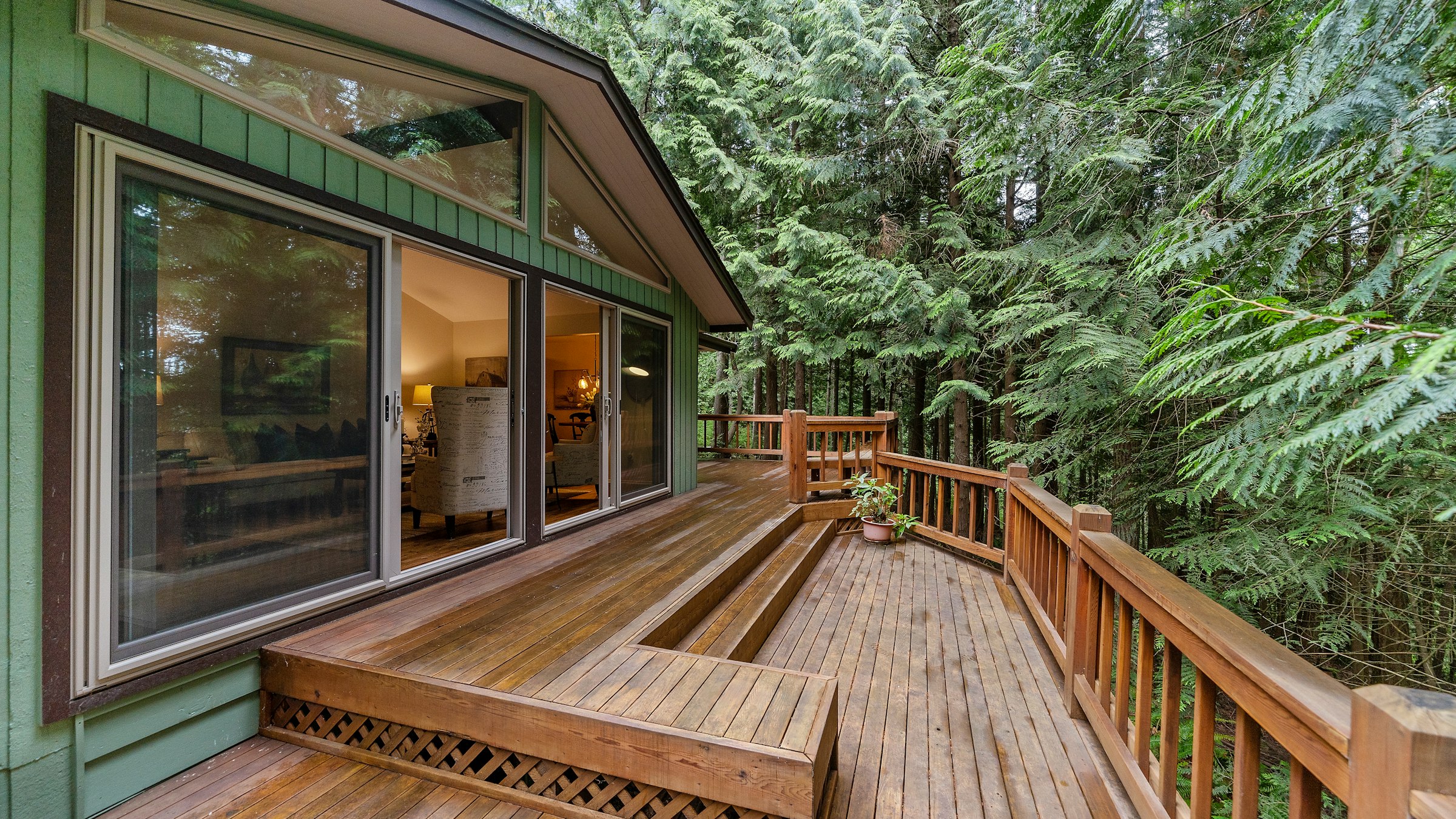 A wooden deck outside a glass door, surrounded by forest