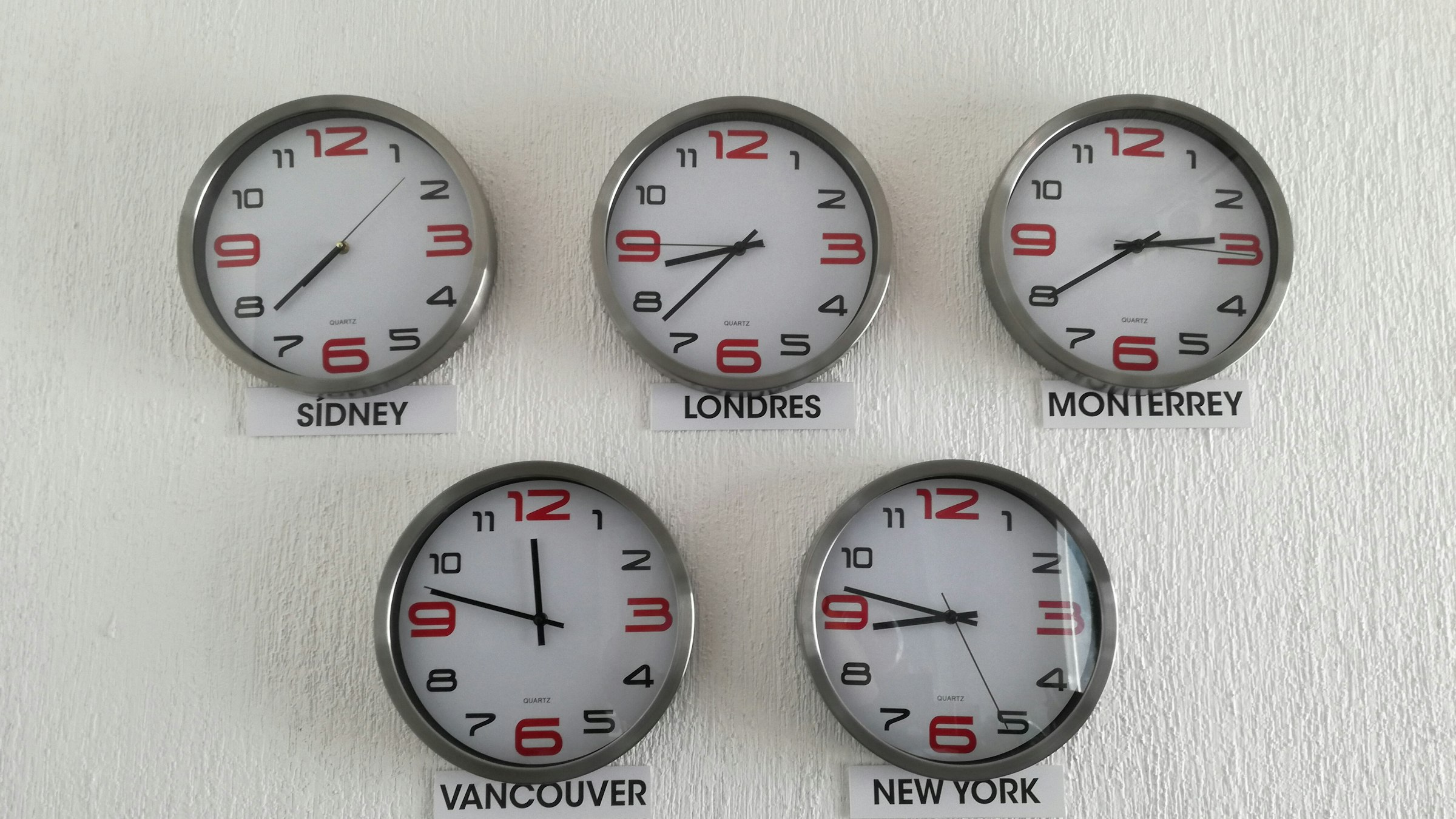 Wall clocks showing the time in different cities, including New York