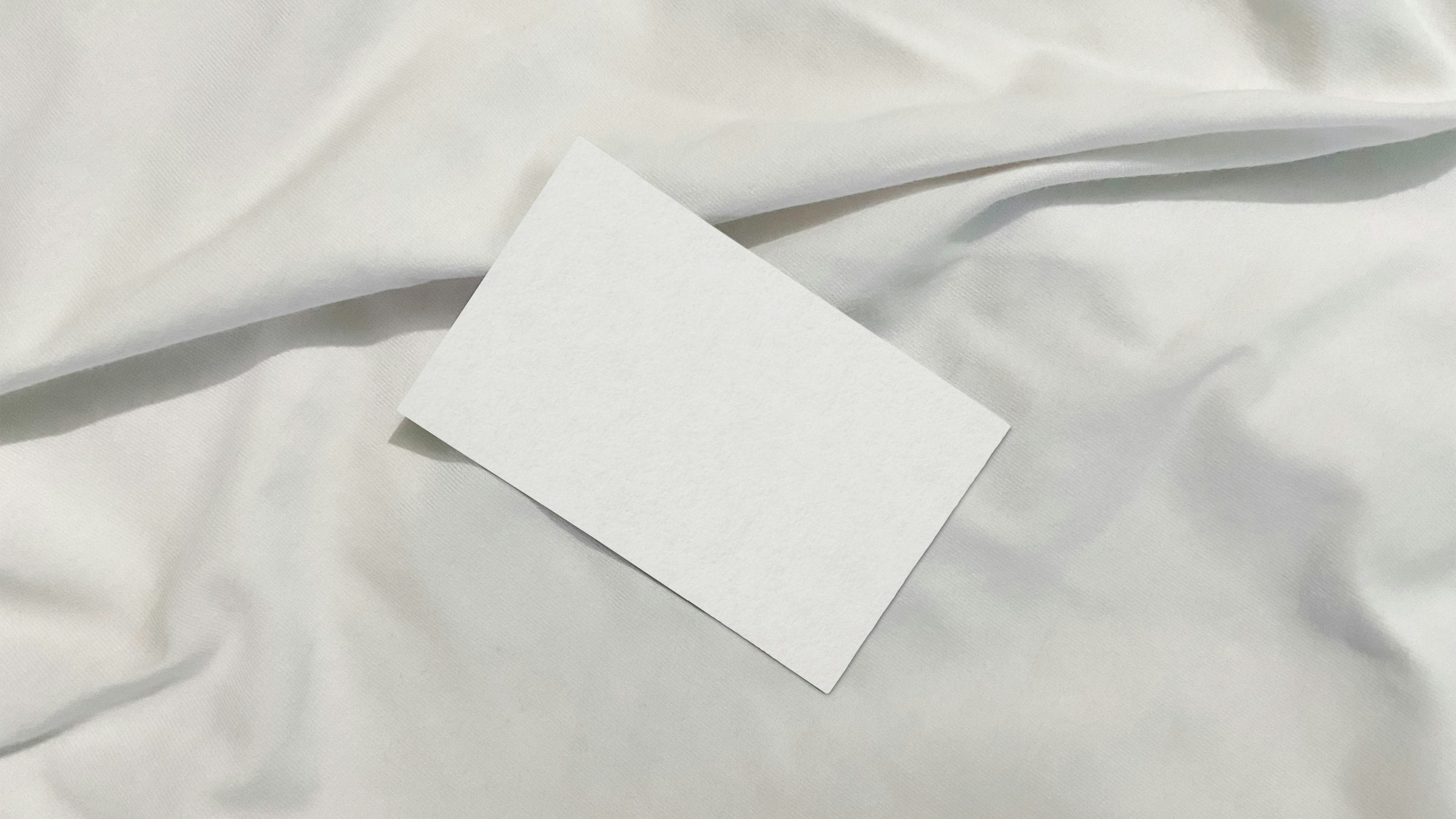 A blank card resting on soft white fabric