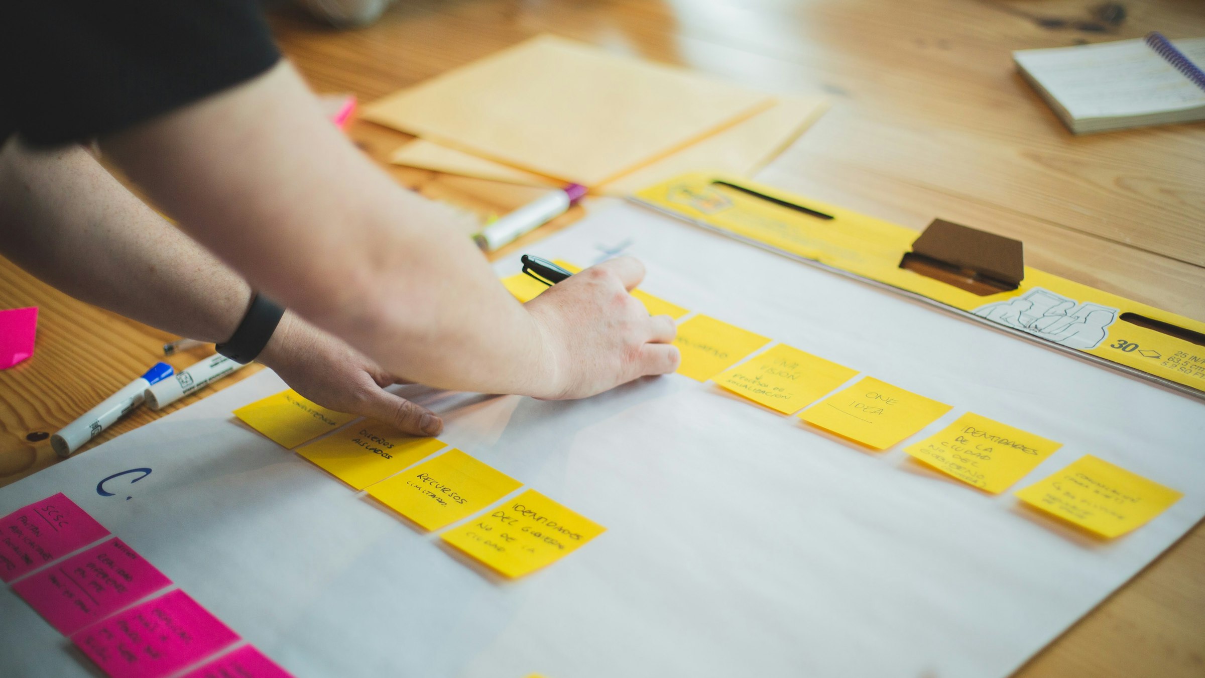Hands arranging colorful sticky notes on a planning board