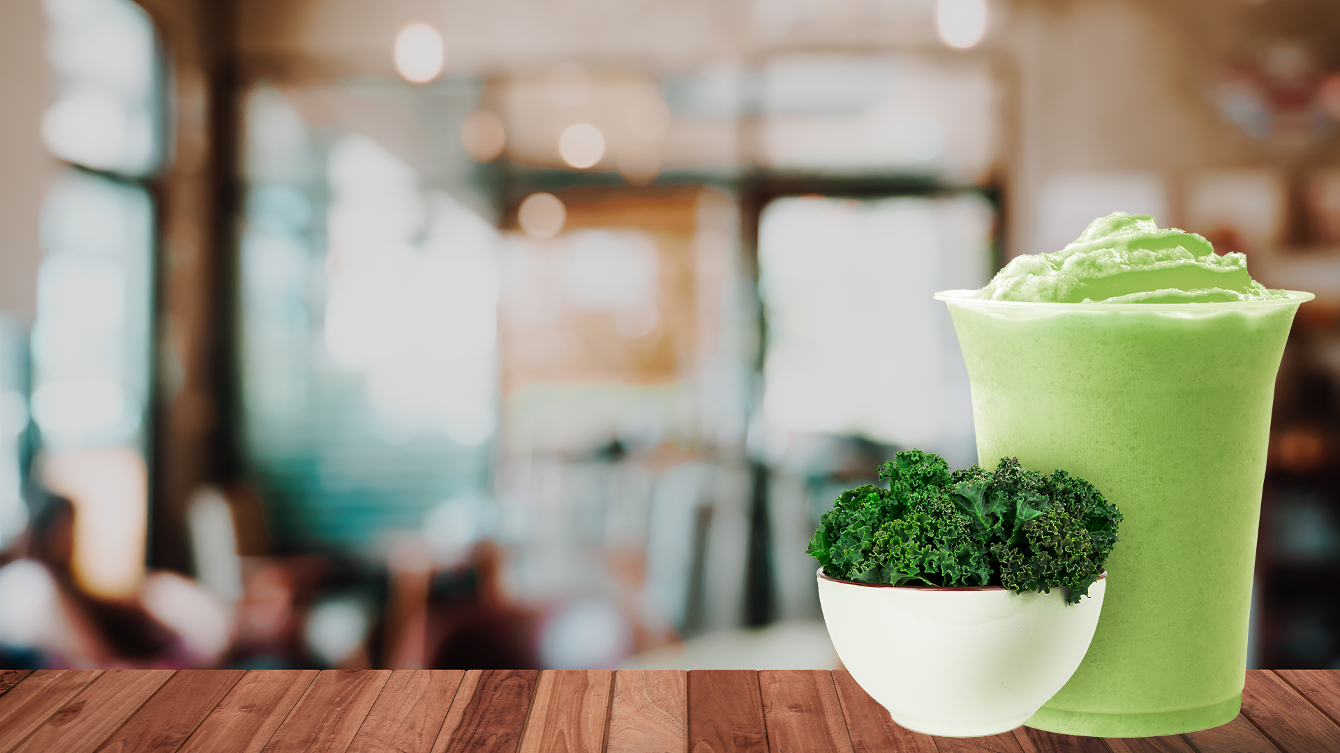 Green protein shake next to a bowl of Kale on cafe counter top