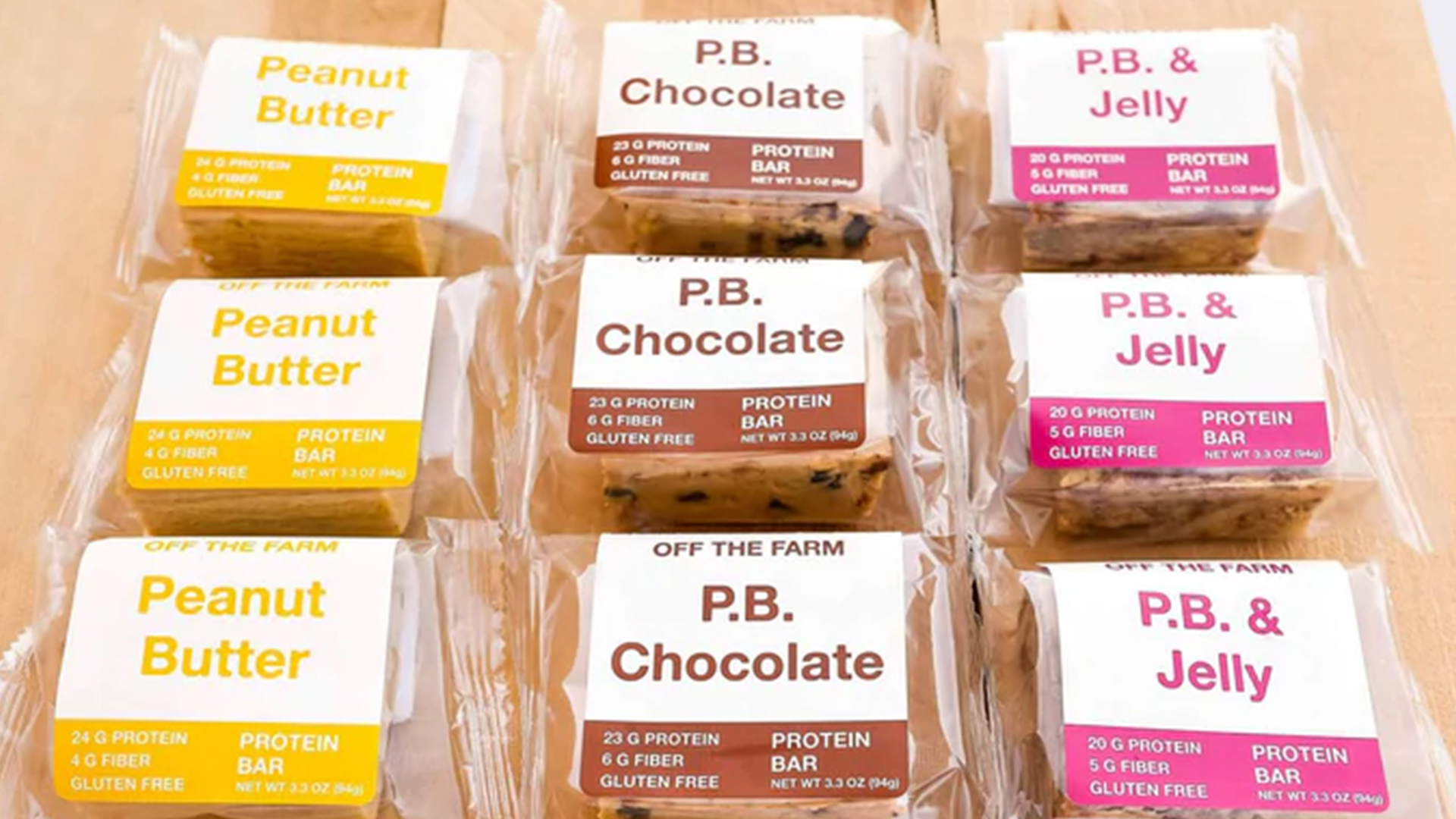 Three Flavors of Off the Farm Bars: Peanut Butter, PB Chocolate and PB & Jelly on Wood Table