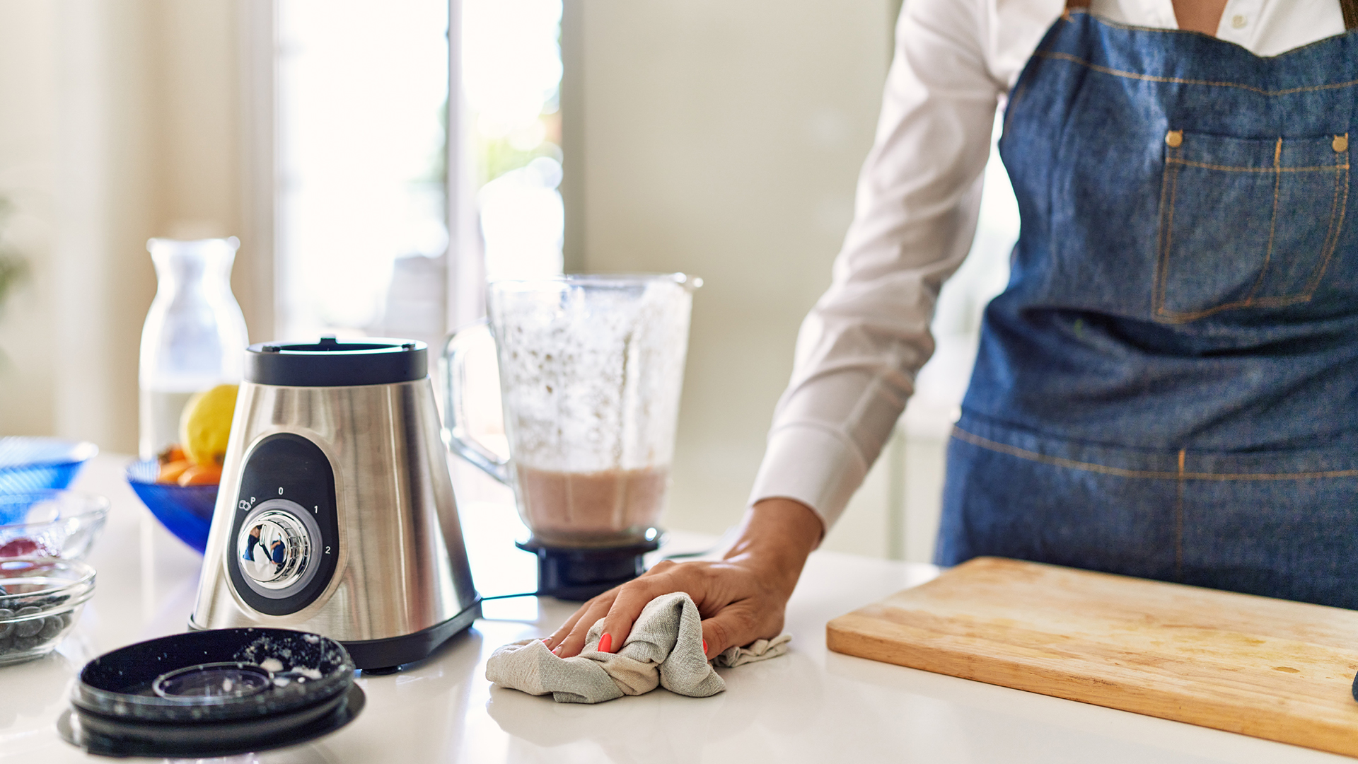 Person cleaning counter top and smoothie blender