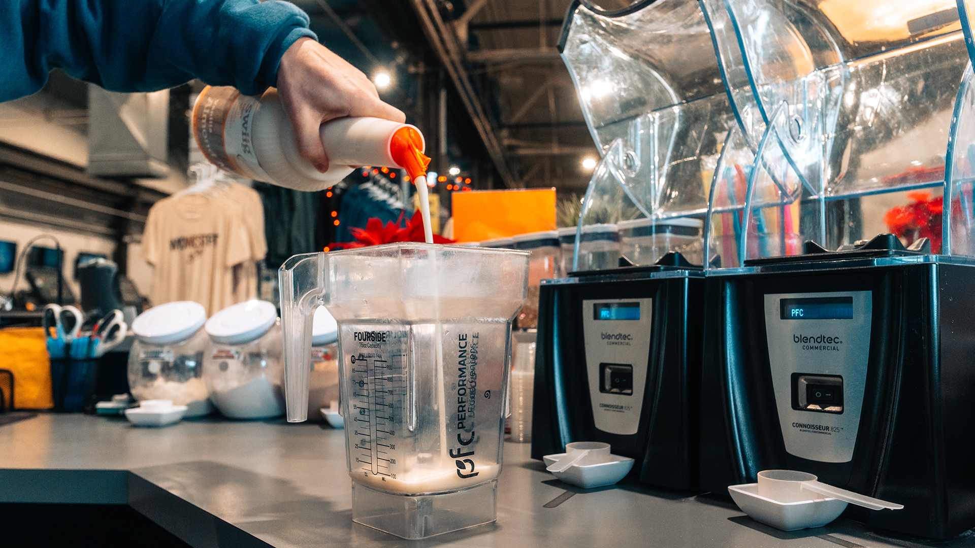 Close Up of Employee Pouring swiig Vanilla Almond Milk into a Blendtec Blender Behind a Juice Bar Counter