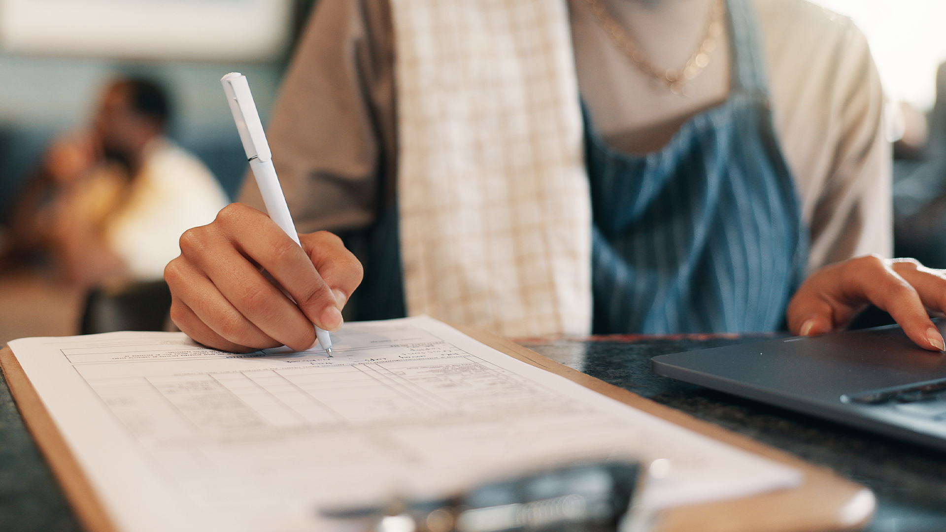 woman in work attire filling out a permit application in their restaurant