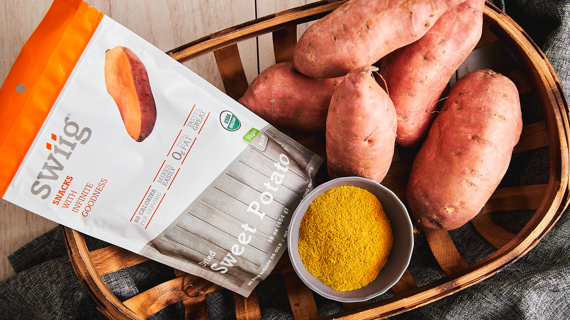 swiig Dried Sweet Potato bag in a wooden basket surrounded by sweet potatoes