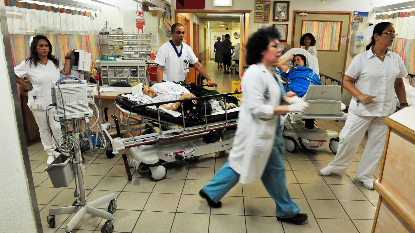 Nurses and physicians busy in a hospital space with patients in bed.