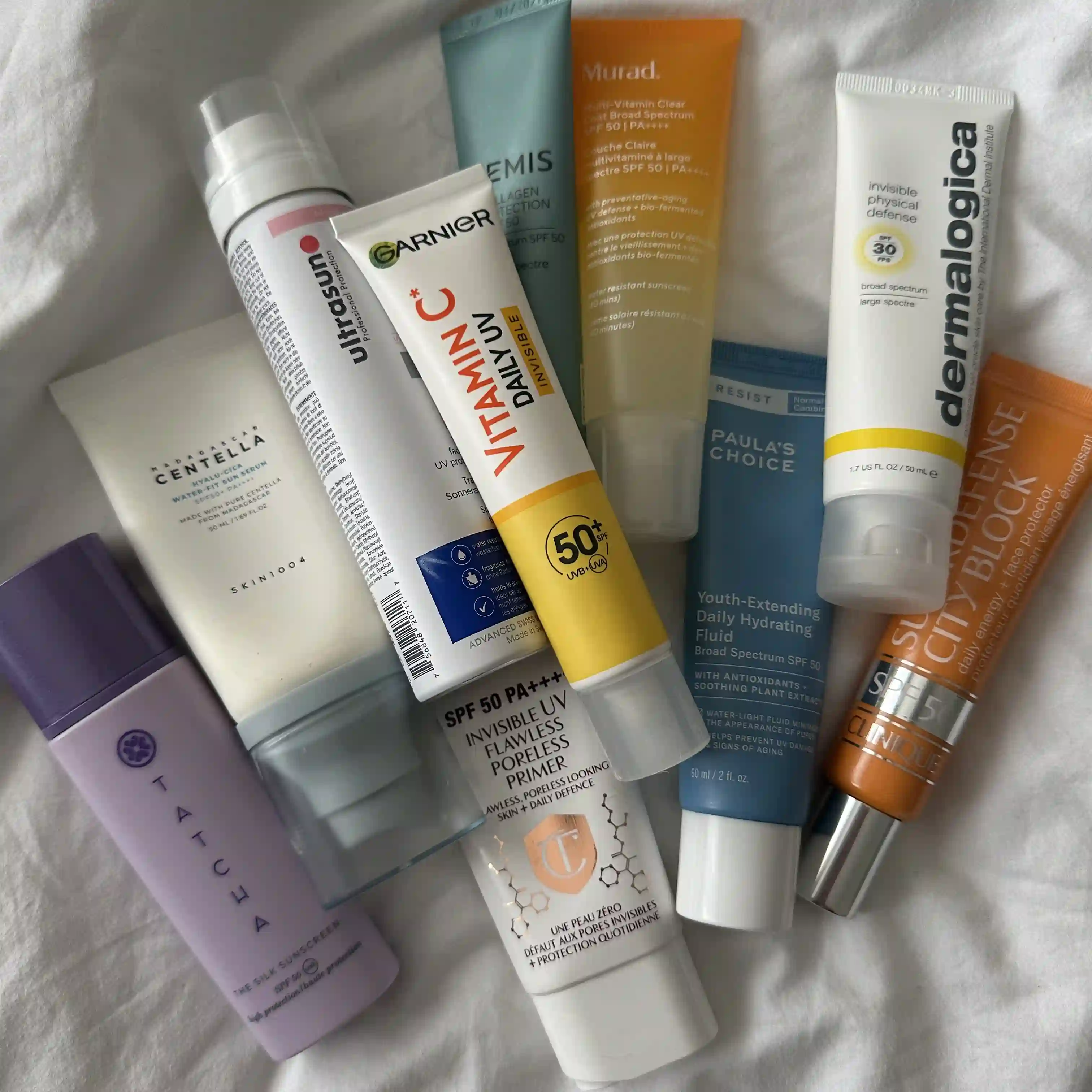 Photo of 10 sunscreens all together lying on a white sheet