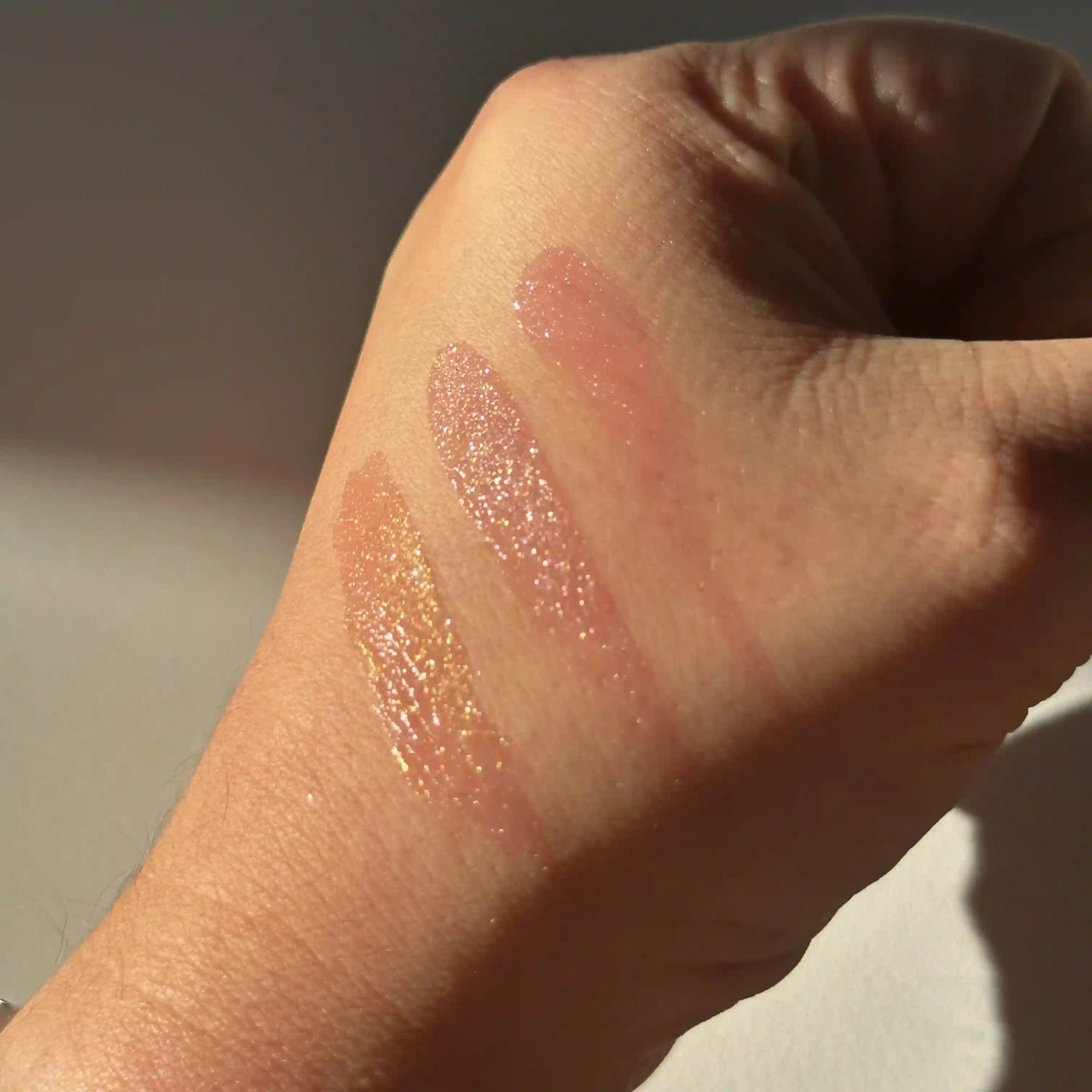 swatches of the Glitter LipTone shades on the side of writers hand against a white back ground in the sunlight