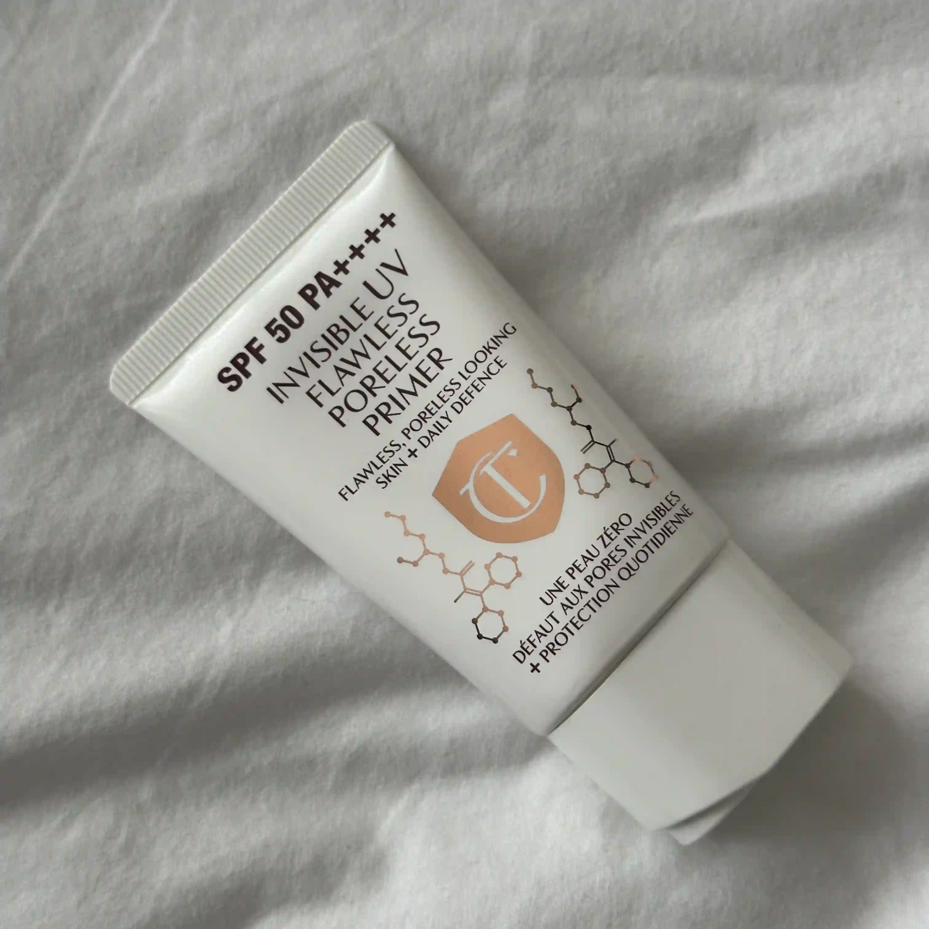 Image Charlotte Tilbury Invisible UV Flawless Poreless Primer laying on a white sheet