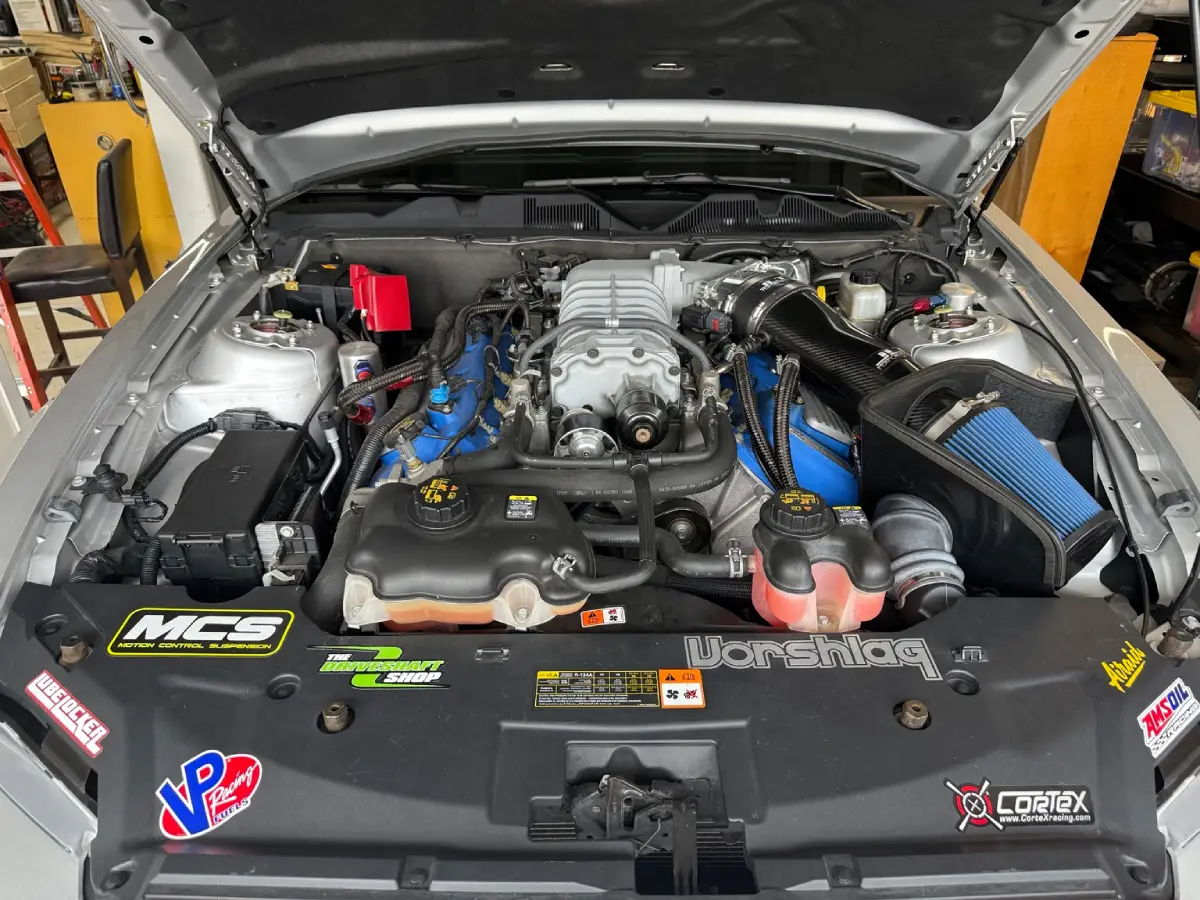 Shelby GT500 engine bay before the cooling overhaul, with the factory engine-coolant and intercooler reservoirs at the front.
