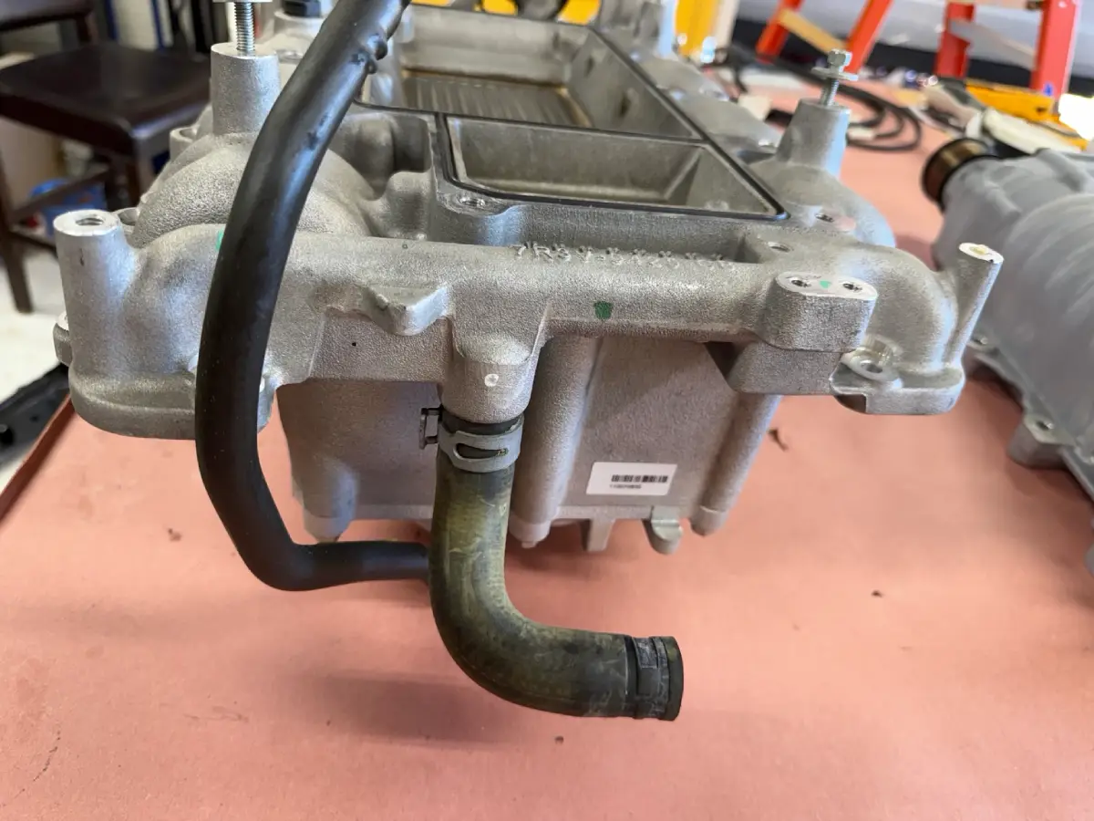 Rear coolant hose and spring clamp on the GT500 intake manifold, shown on the workbench.