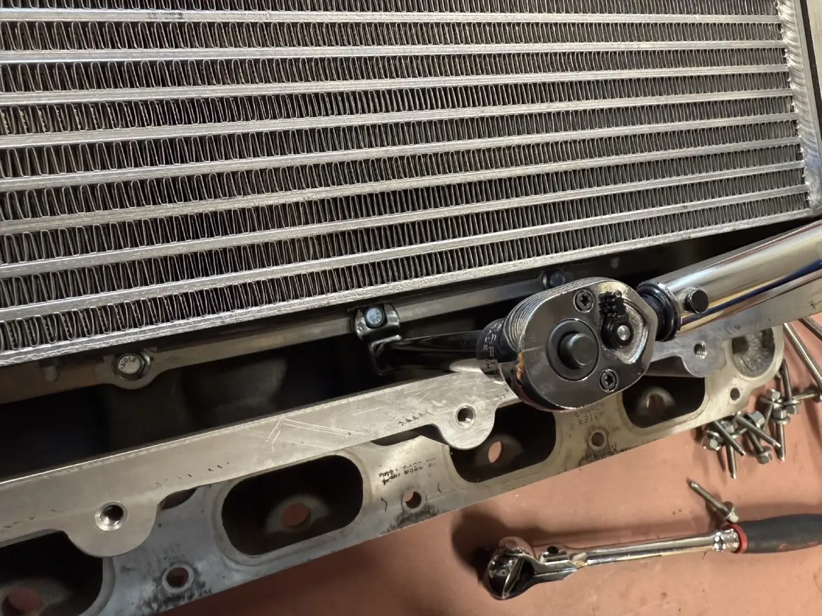 Crowfoot wrench accessing a VMP intercooler mounting bolt in the narrow space beside the core.