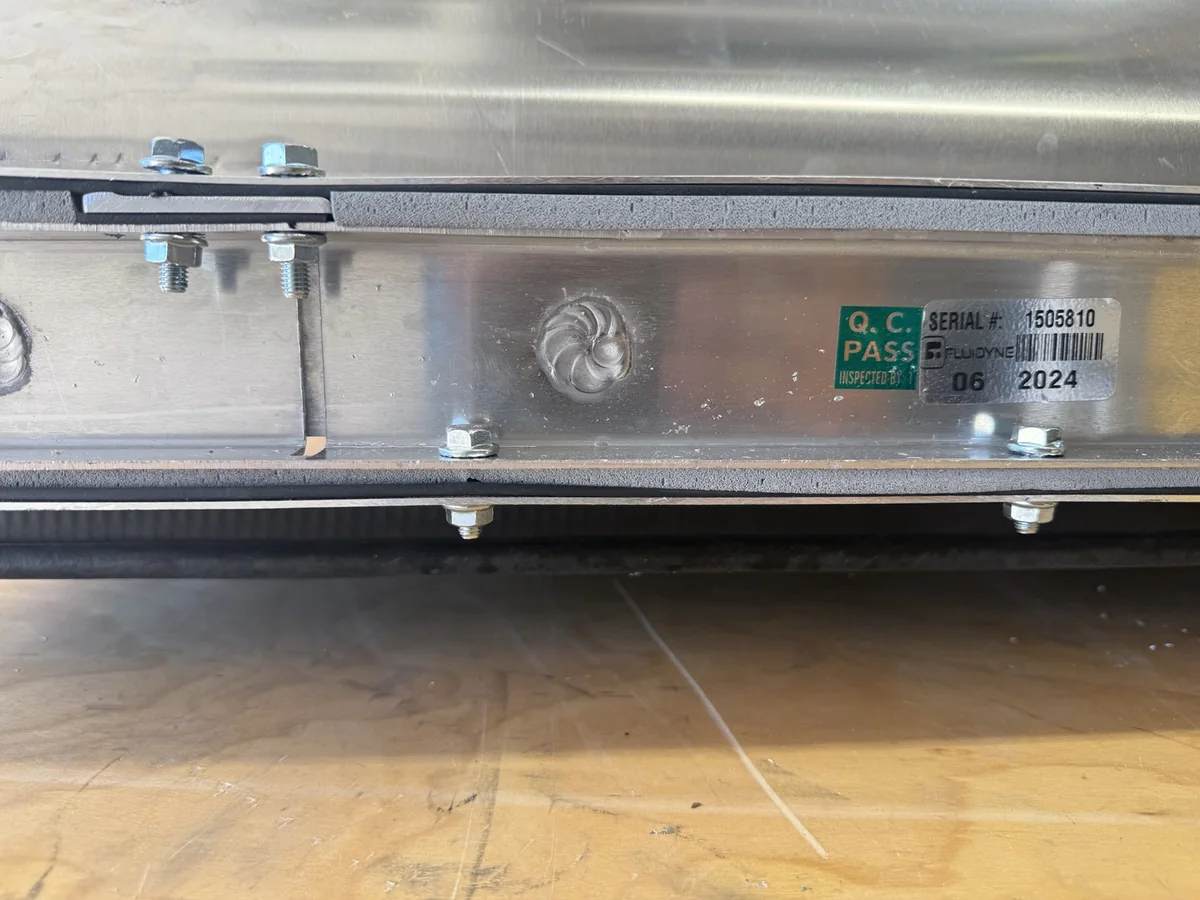 Close-up of sealing strips at the radiator outlet duct interface around an aluminum fan mount.